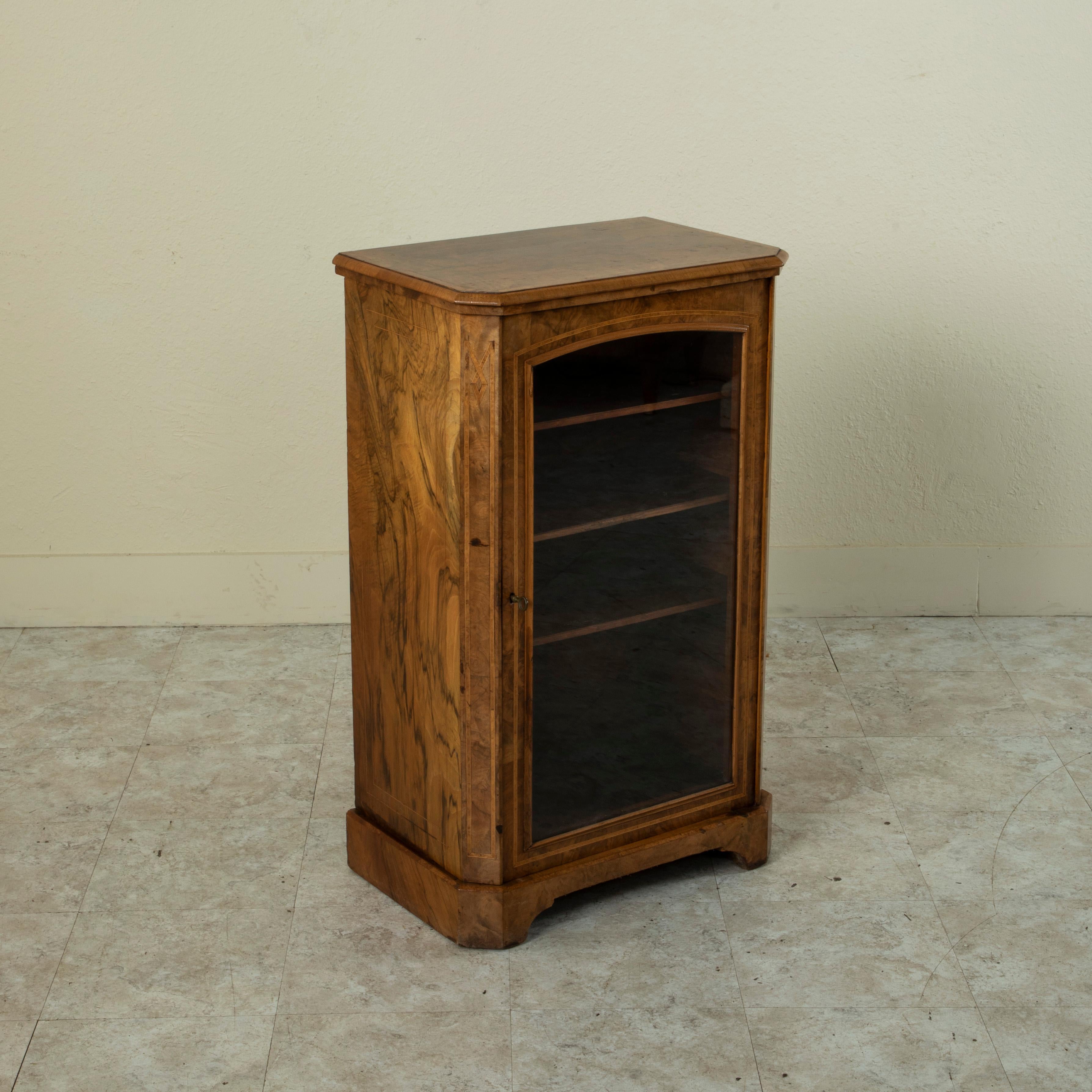 Standing at 36.5 inches in height, this small scale French burl walnut vitrine from the turn of the twentieth century features inset borders made of fine lines of inlaid lemonwood and elm. Its single glass door opens to reveal an interior with three