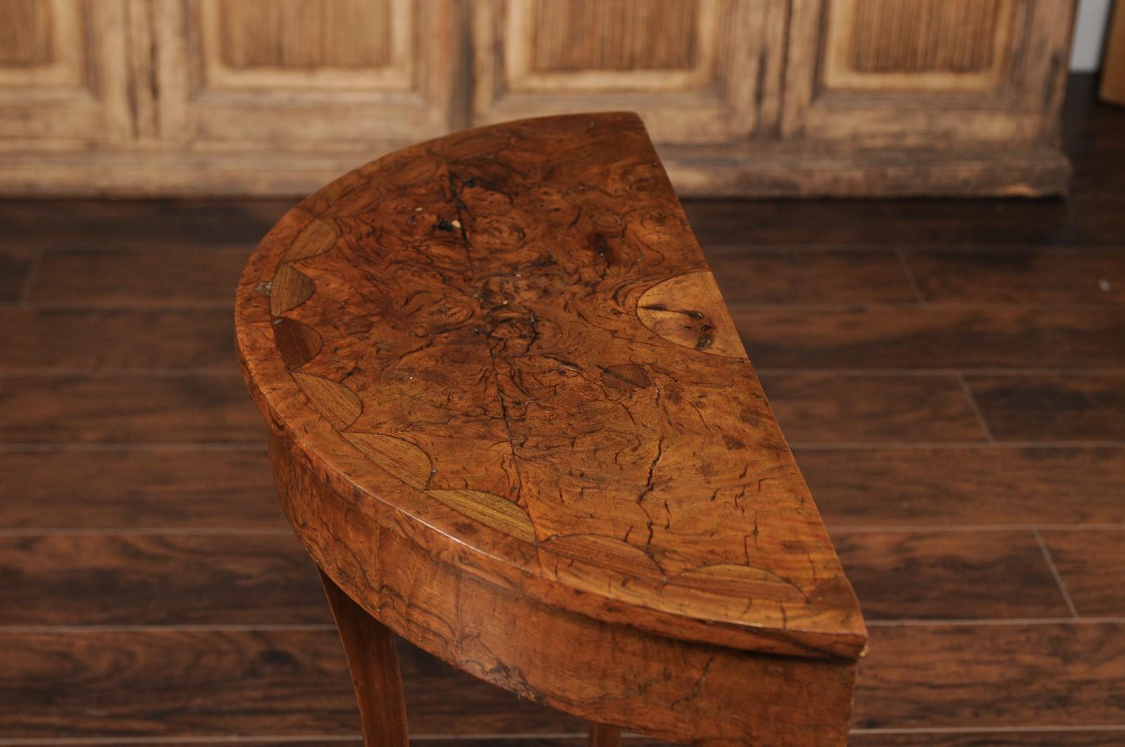A French burl wood demilune console table from the early 20th century, with petite drawer, curving legs and lower shelf. Born in France during the Belle époque era, this exquisite demilune console table features a semi-circular top with delicately