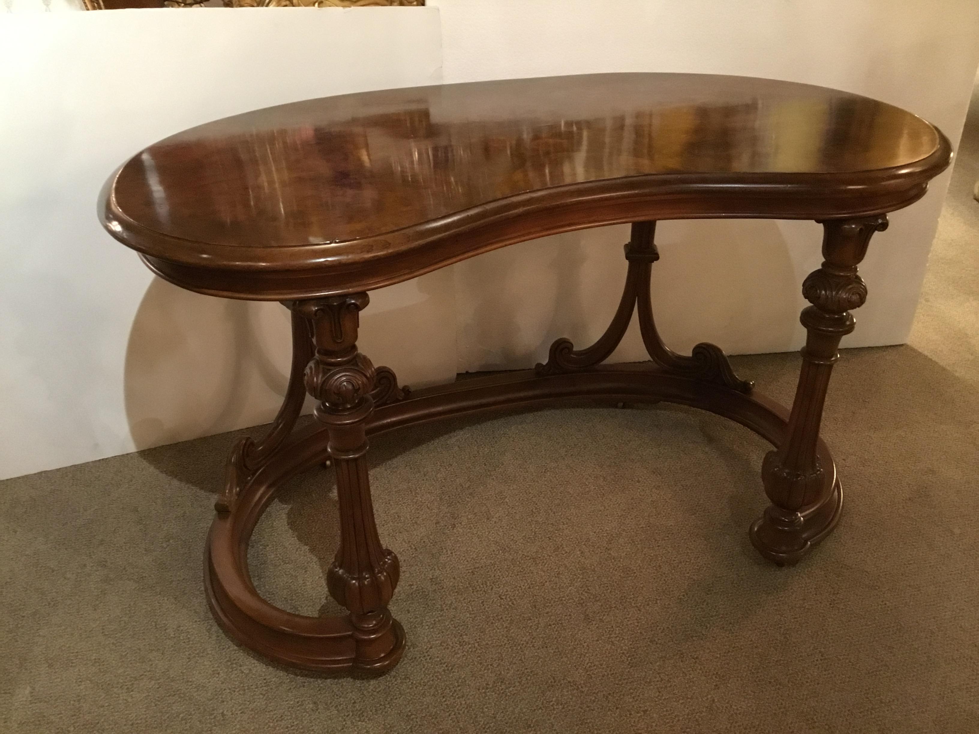 French burl wood kidney form writing desk, 19th century, having a kidney-shaped top,
over foliate carved columns and back supports, on curved stretcher base, rising on casters.