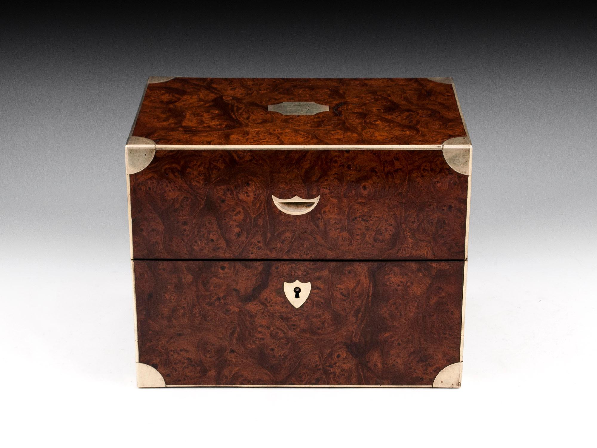 Antique jewelry box veneered in stunning burr elm with brass edging, engraved initial plate, finger tab and shield shaped escutcheon. With flush brass carry handles on each side. The engraved initial plate is adorned with a coat of arms. 

The