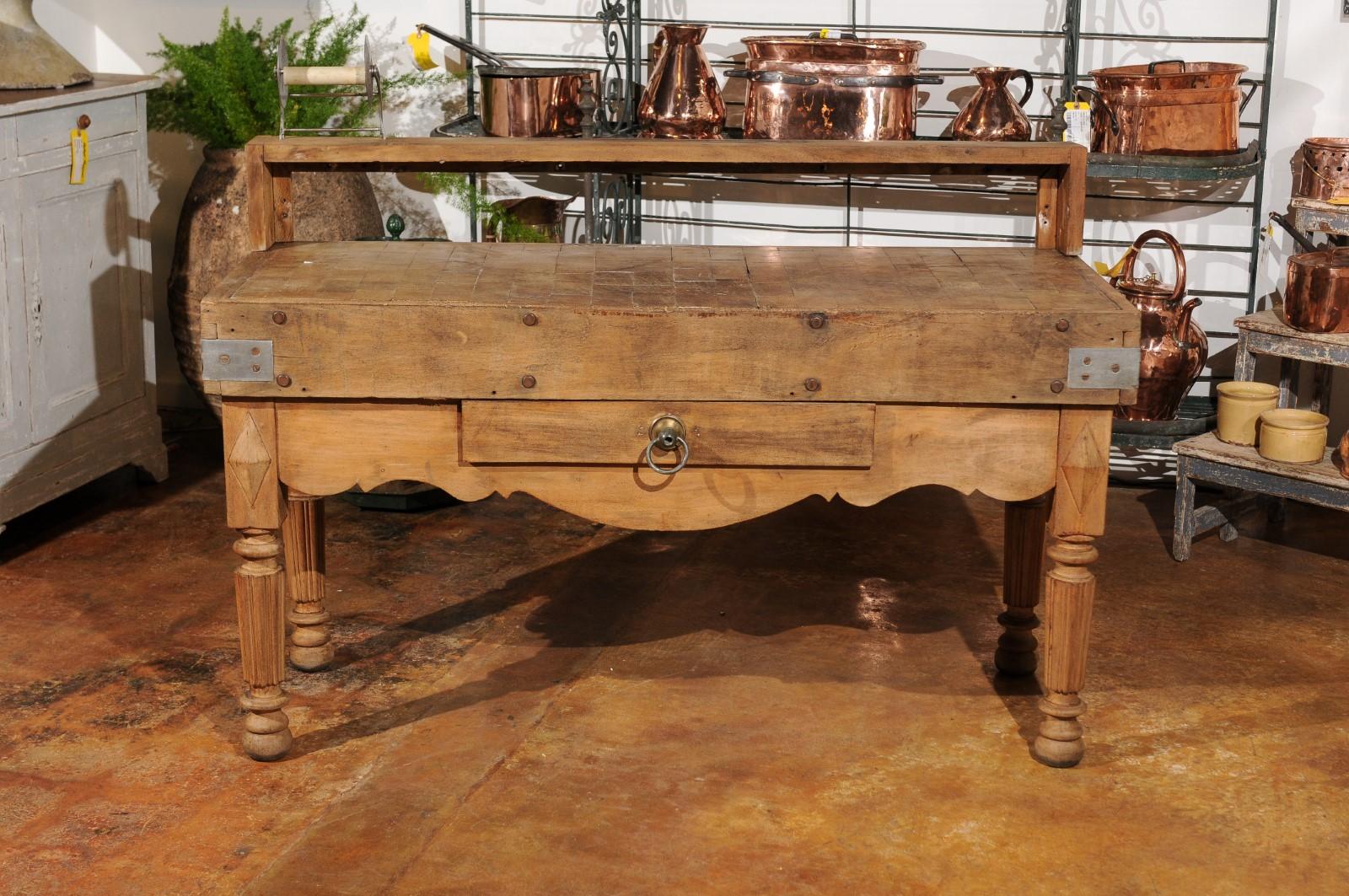 A French butcher block table from the 19th century, with single drawer, utensil holder and carved apron. Born in France during the 19th century, this chopping work table features a rectangular top with utensil holder, sitting above a nicely