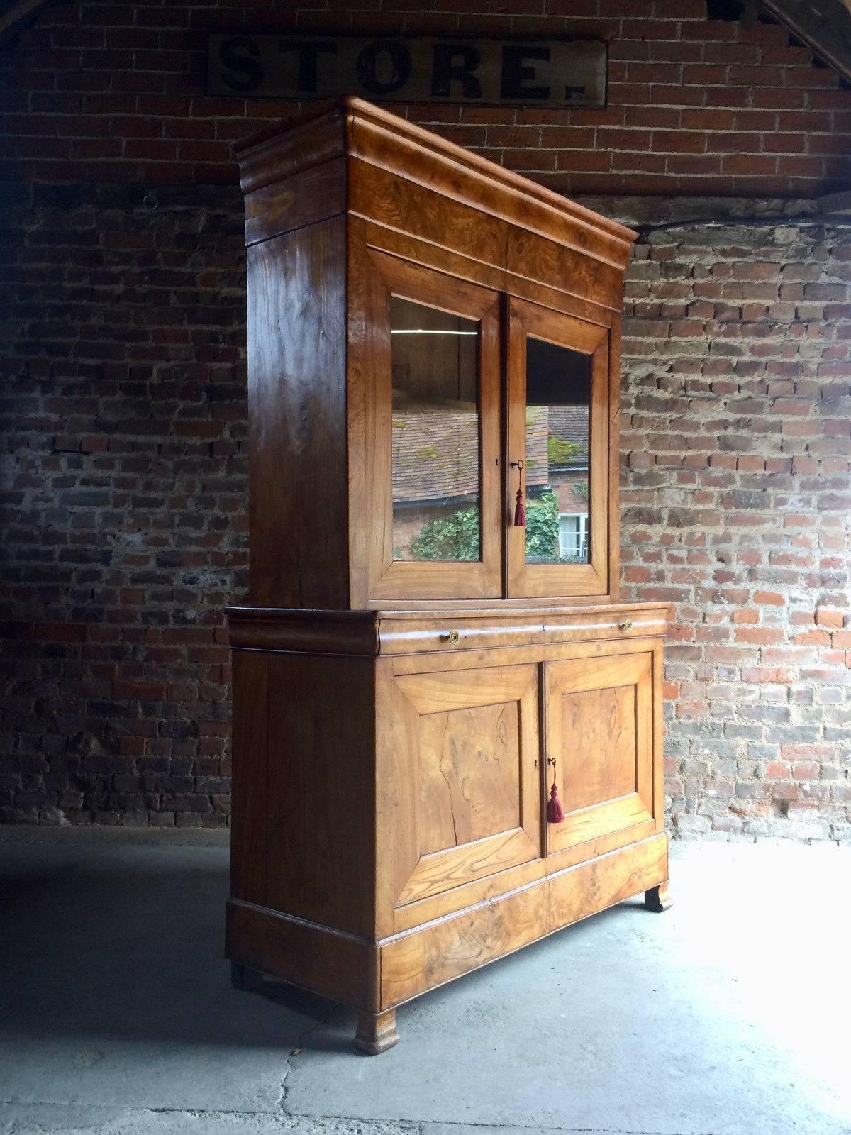 A magnificent Napoleon III 19th century French elm and burr-elm tall cabinet, circa 1850, the upper part with molded cornice and enclosed pair of glazed doors, the base fitted full-widh shallow drawer with brass knob handles, above a pair of panel