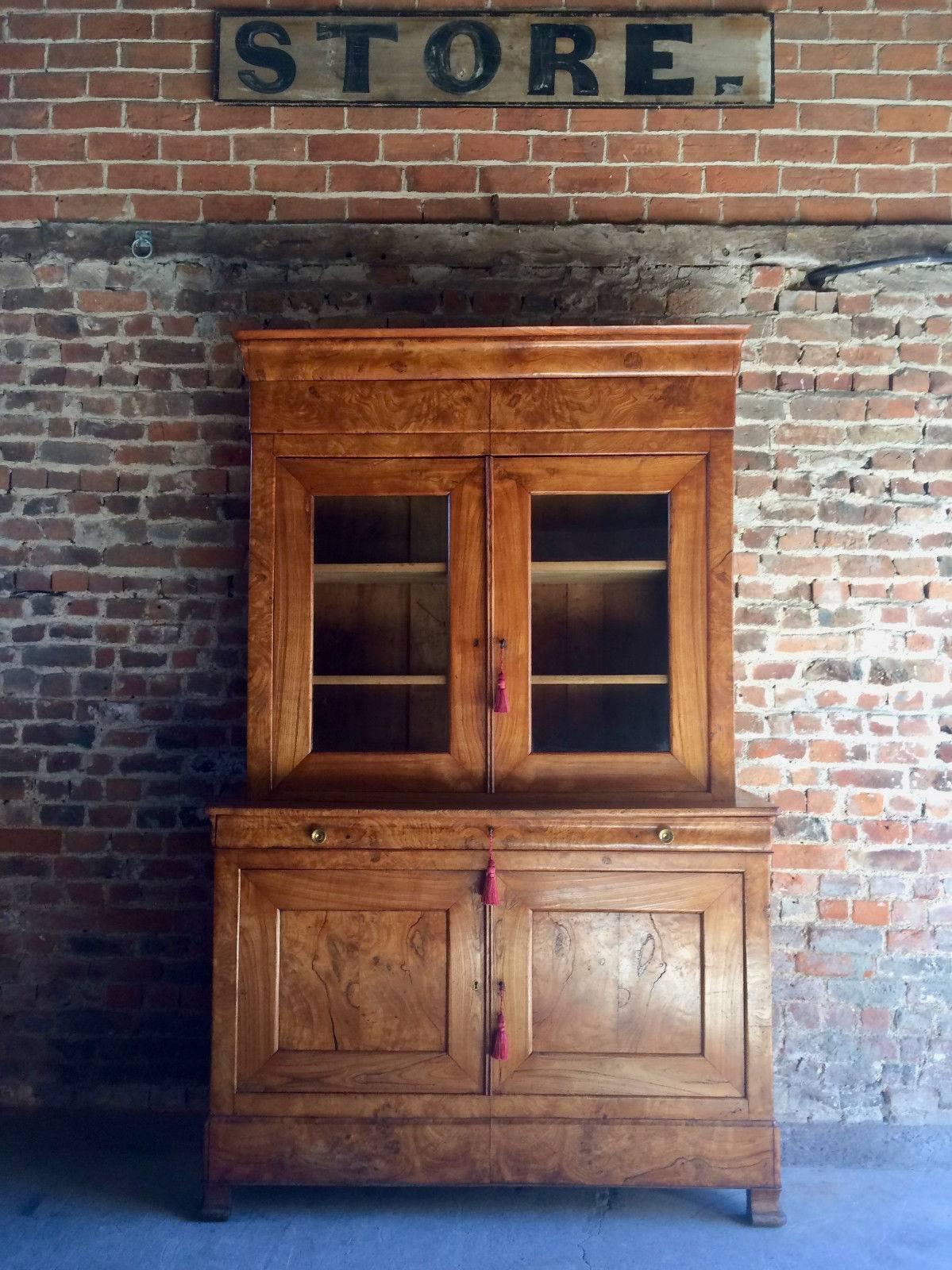 A magnificent Napoleon III 19th century French elm and burr-elm tall cabinet, circa 1850, the upper part with moulded cornice and enclosed pair of glazed doors, the base fitted full-widh shallow drawer with brass knob handles, above a pair of panel