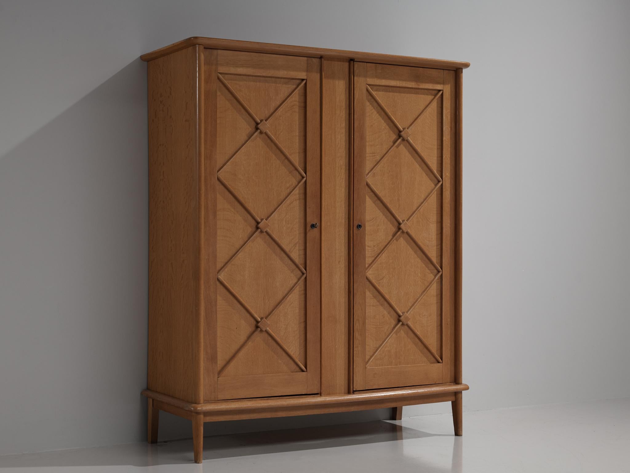 Large cabinet, oak, France, 1950s

An elegant case piece in oak that features geometric details on the doors. The high board is lifted from the ground by slim, conical legs that give the solid looking body a more airy appearance. The cabinet