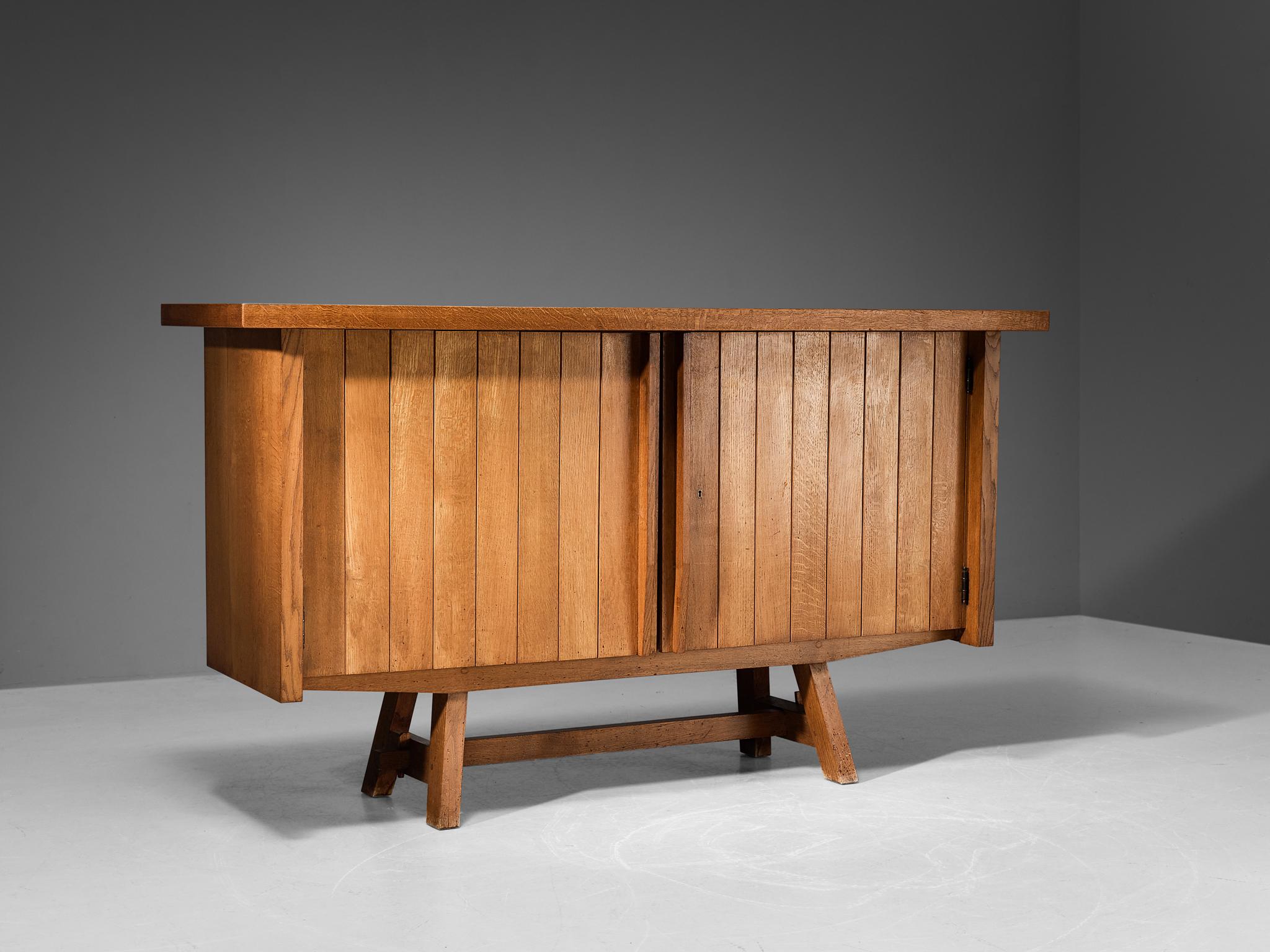 Cabinet, oak, France, 1960s

This elegant sideboard in solid oak provides great storage space. The door panels are composed of carved vertical lines, adding a rhythmic and haptic surface to the front. The corpus is supported by tapered legs, which
