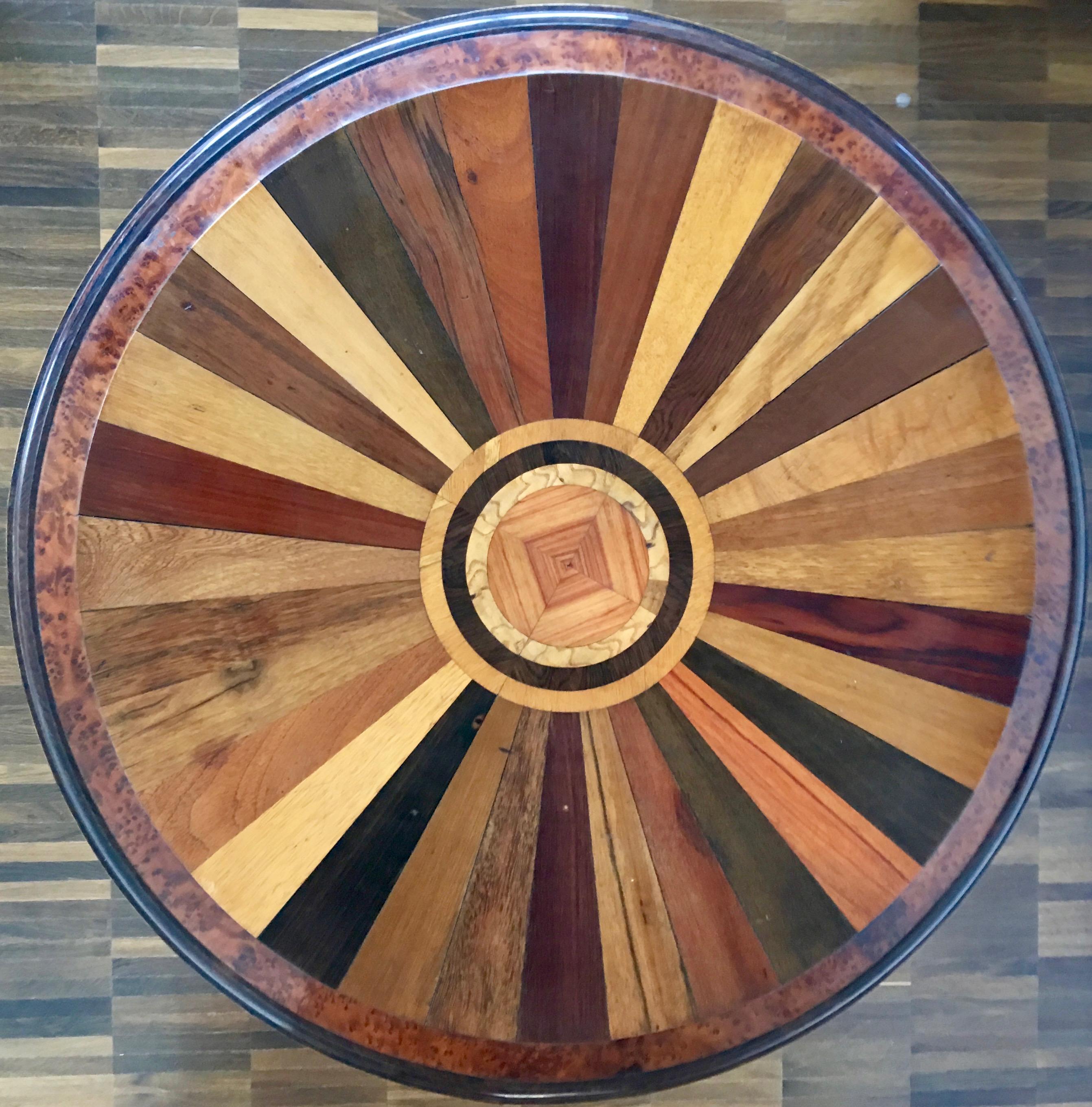 Runder Tisch eines französischen Schreiners, zweite Hälfte des 19. Jahrhunderts.
Ein sehr hochwertiger Beistelltisch; die runde, mit ca. 35 verschiedenen Holzarten furnierte Platte steht auf einem gedrechselten, mit Ebonit und Wurzelholz furnierten
