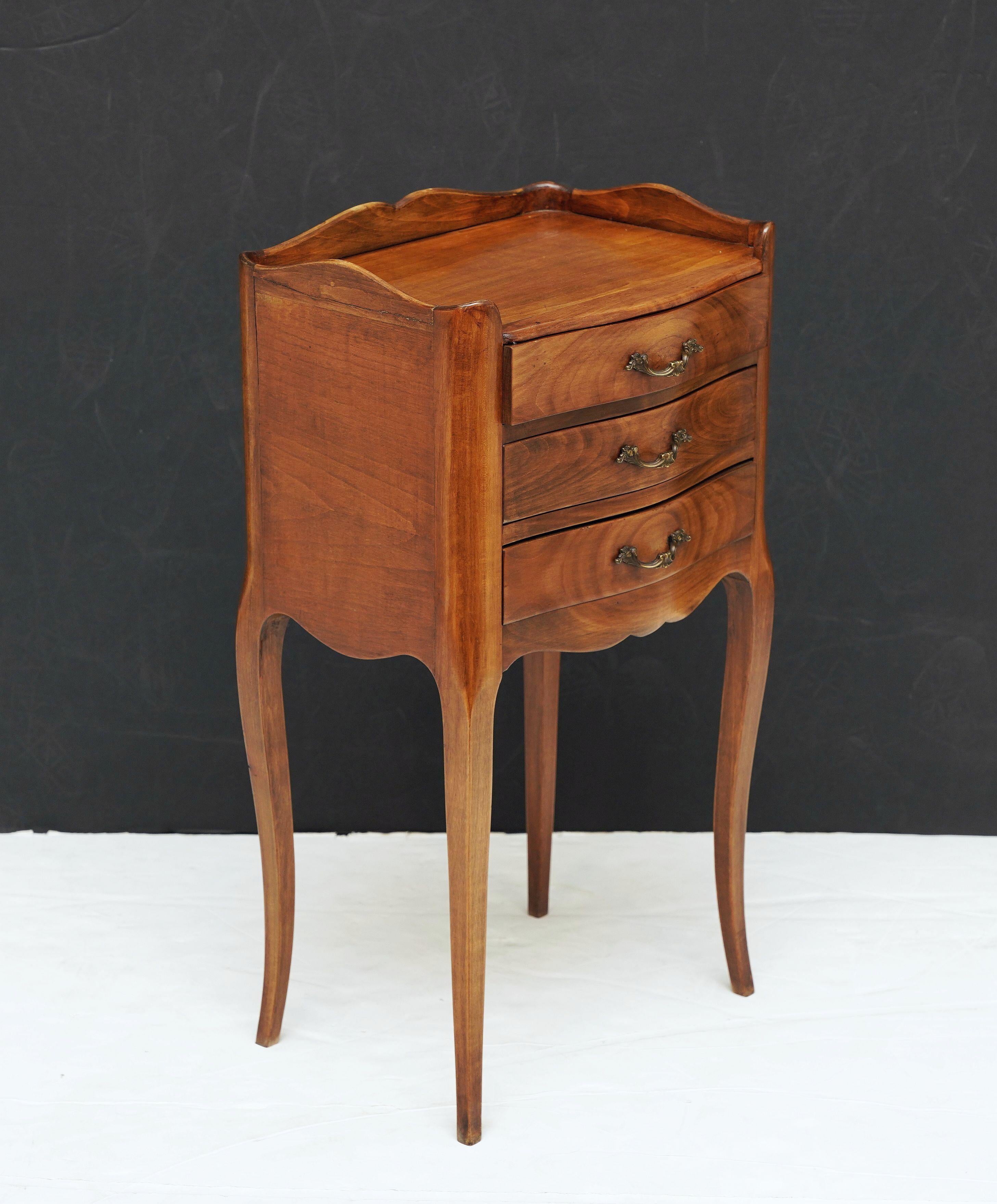 Une belle paire de tables de chevet ou de tables de nuit françaises en merisier merveilleusement patiné - chaque table présente une galerie à bord festonné sur une frise serpentine de trois tiroirs avec des poignées originales en bronze doré, un