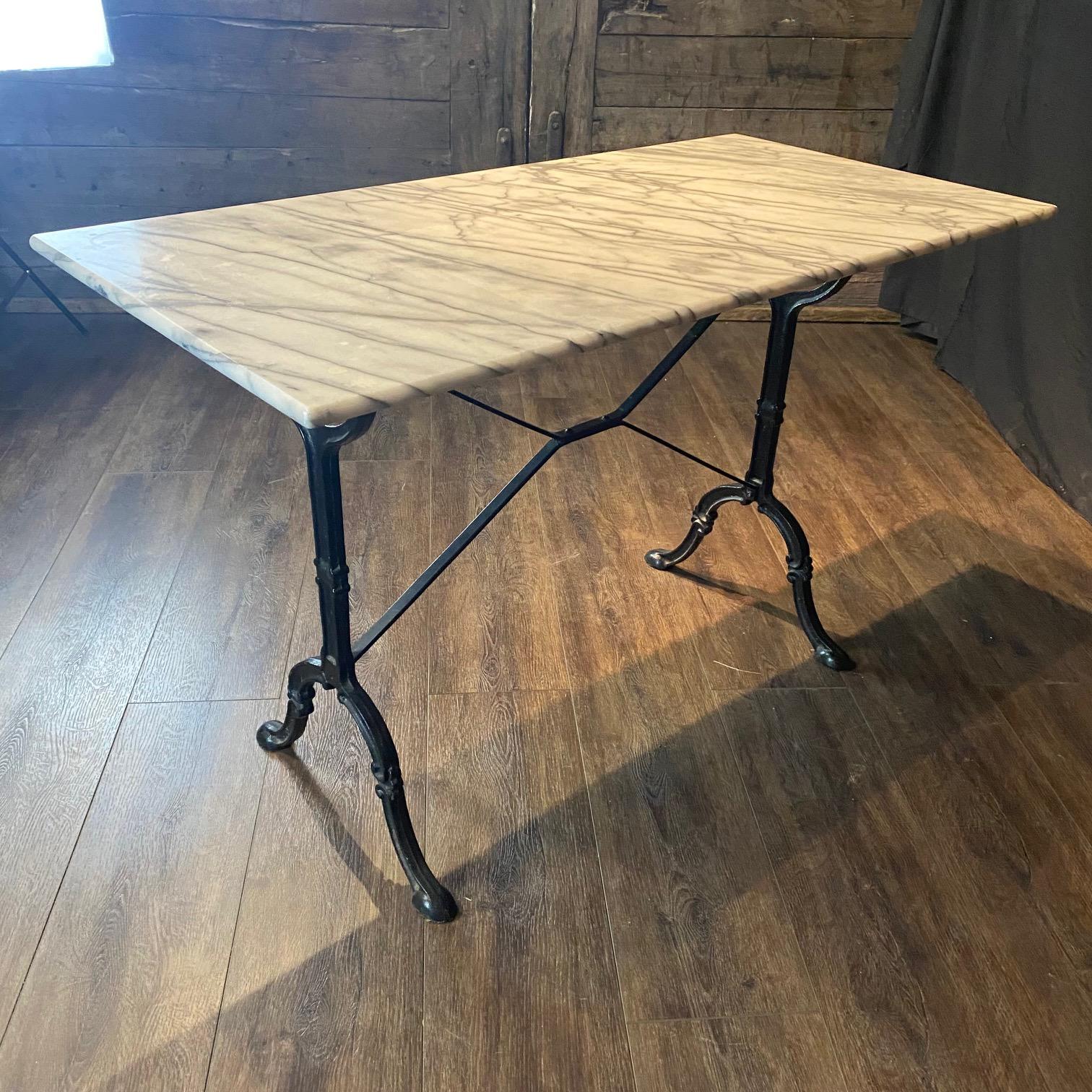 Classic and versatile French marble top cafe table or writing desk with a black iron base. The tabletop marble is a luxurious Carrara white with gray veining marble  - and whether used in a cafe, restaurant, or garden or home setting, this table