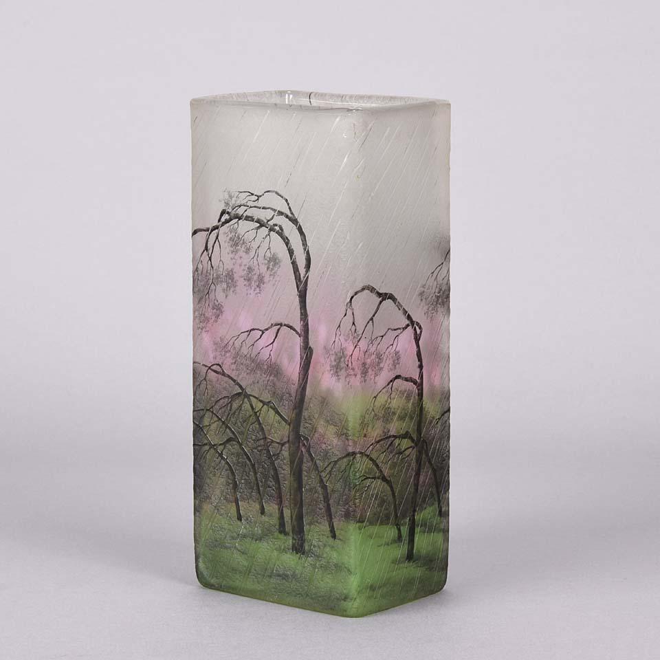 A stunning and very rare cameo glass vase etched and enameled with a fabulous landscape of silver birch trees blown in the wind and the rain, exhibiting excellent colors of deep pink and greens and very fine surface detail, signed Daum Nancy and