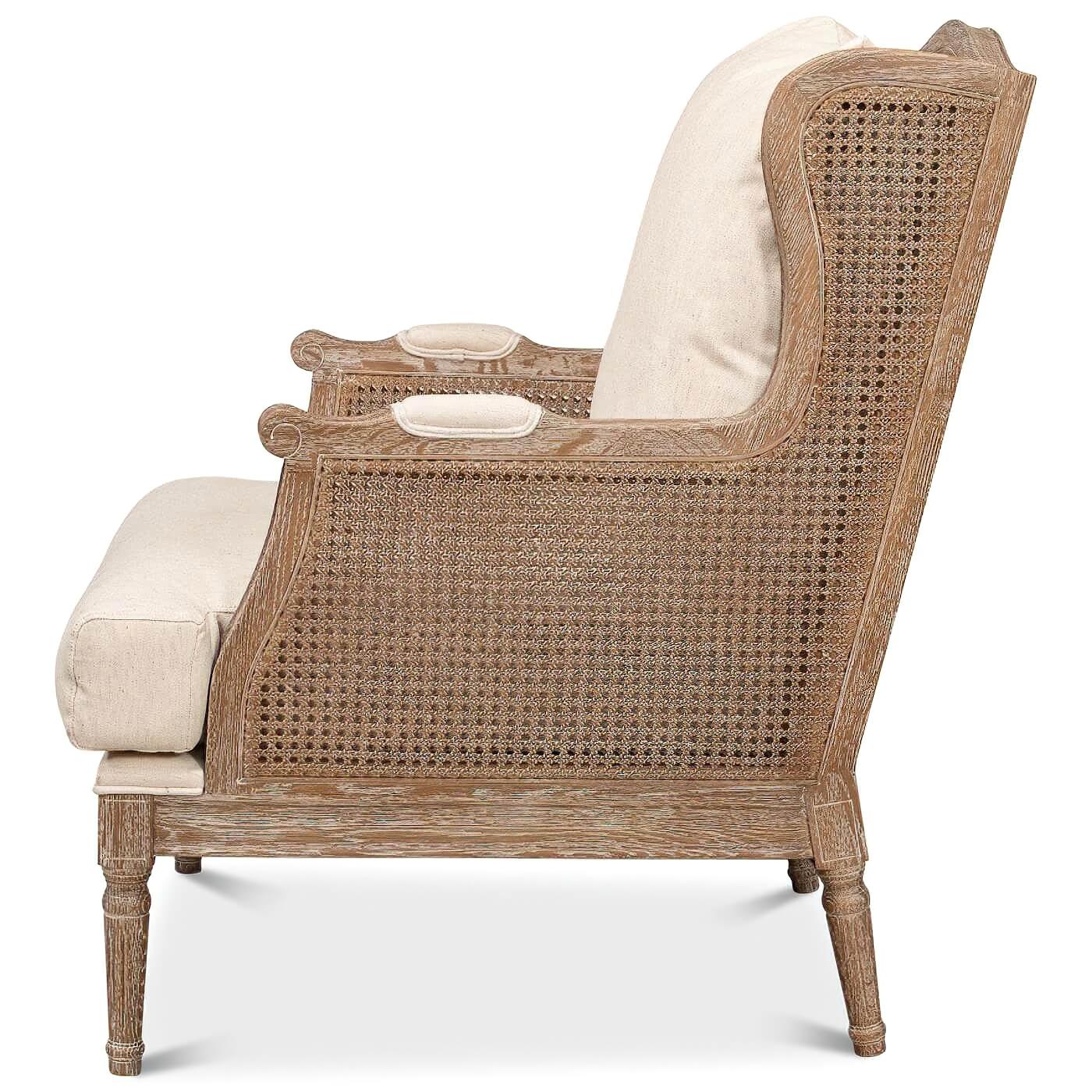 Fauteuil à oreilles de style Louis XVI, blanchi à la chaux, avec dossier et côtés en rotin. Cette magnifique chaise est dotée d'une assise et d'un dossier en lin ivoire. Elle est fabriquée en chêne blanchi et reçoit une finition transitionnelle