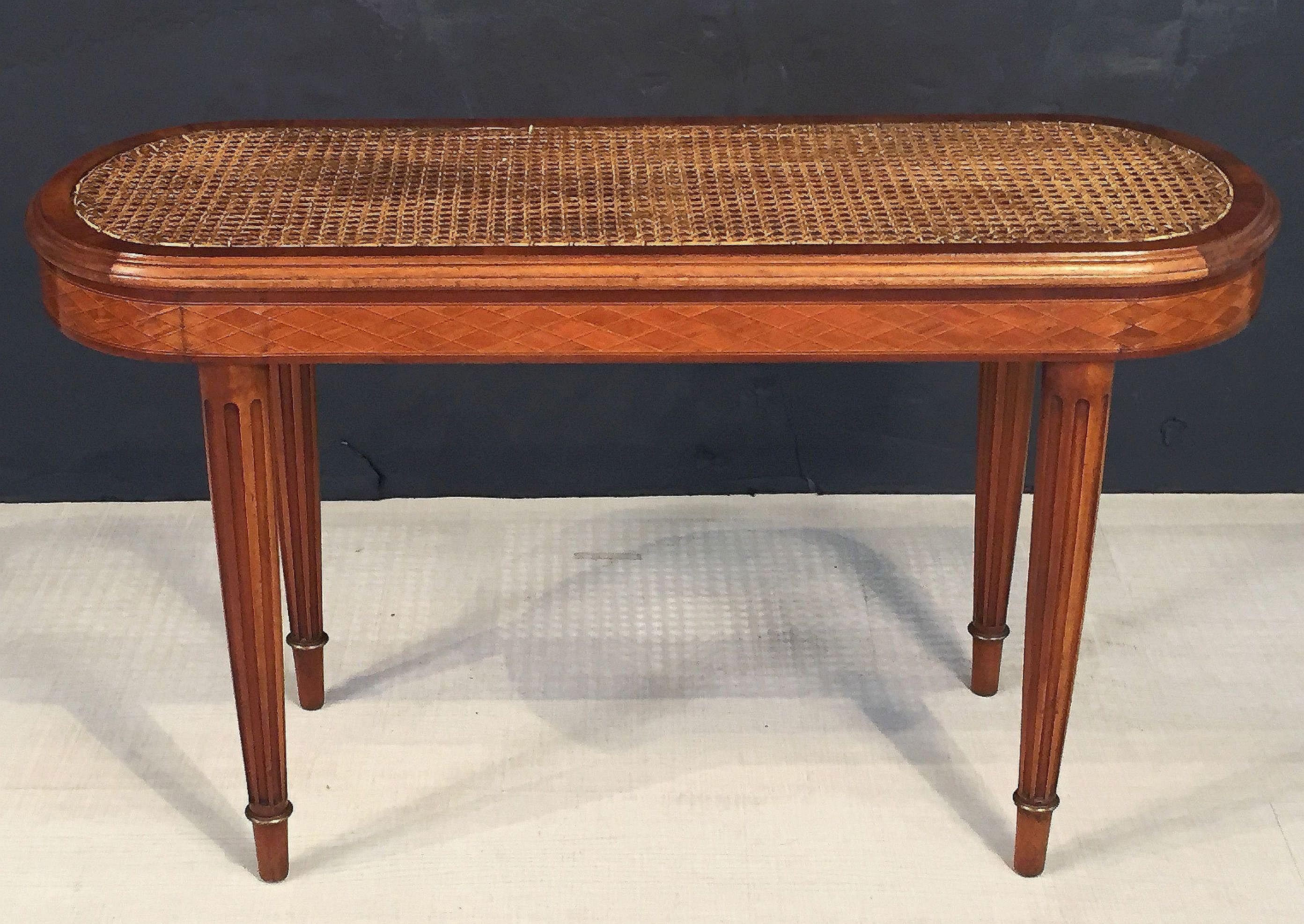 A fine French oval shaped bench of mahogany with inset cane seat and resting on four turned legs, each with brass accents.

Measures: Height 21 inches
Width 36.5 inches
Depth 13 3/4 inches.
  