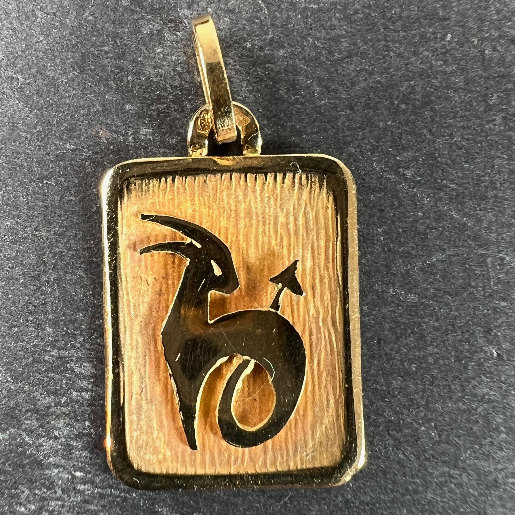 A French 18 karat (18K) yellow gold charm pendant designed as a rectangular medal with an engraved recess depicting a goat-fish hybrid representing the zodiac star sign of Capricorn. Stamped with the eagle’s head for French manufacture and 18 karat
