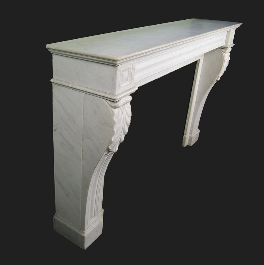 A good quality French Carrara marble chimneypiece of Louis XVI form. The panelled console jambs on plinths are adorned with stylised acanthus decoration. The simple panelled frieze is flanked by corner blocks under a substantial moulded shelf.