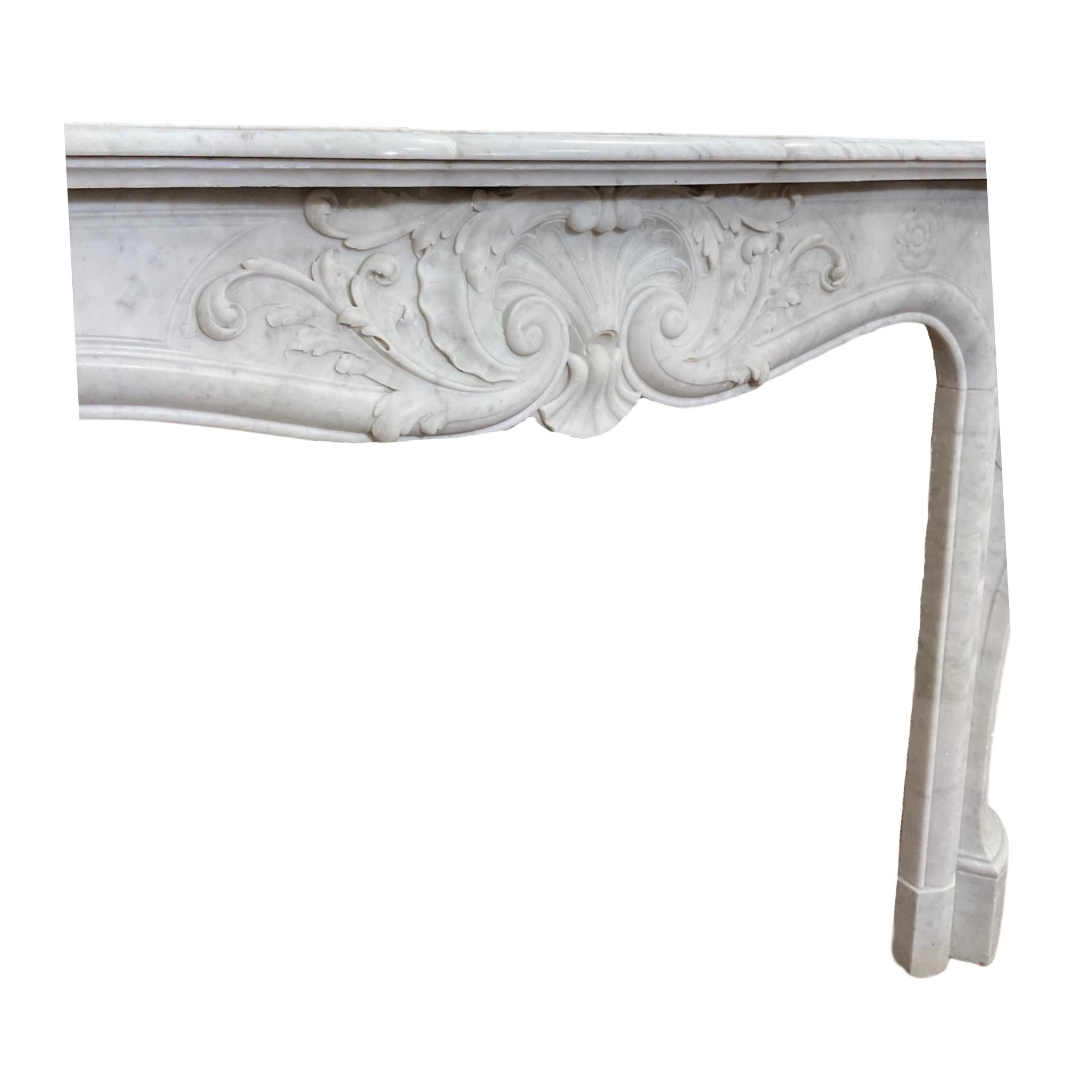 This French Carrara Marble mantel from the 1870s offers a luxurious louis xvi style with intricate carvings throughout the legs and center face. Crafted out of pure Carrara marble, this elegant mantel features a beautiful white color, plus a bronze