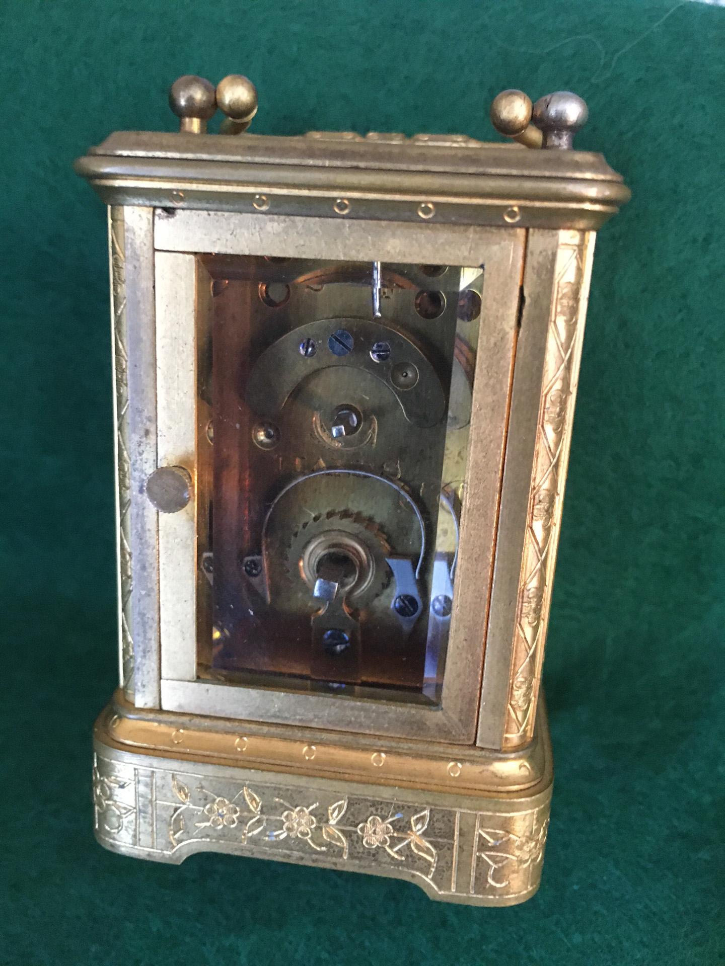 This lovely little jewel of a carriage clock features a profusely floriate engraved gilded Mignonnette No.1 Corniche case with rectangular top. The folding handle is over the oval beveled glass escapement which is
engraved with monogram. The four