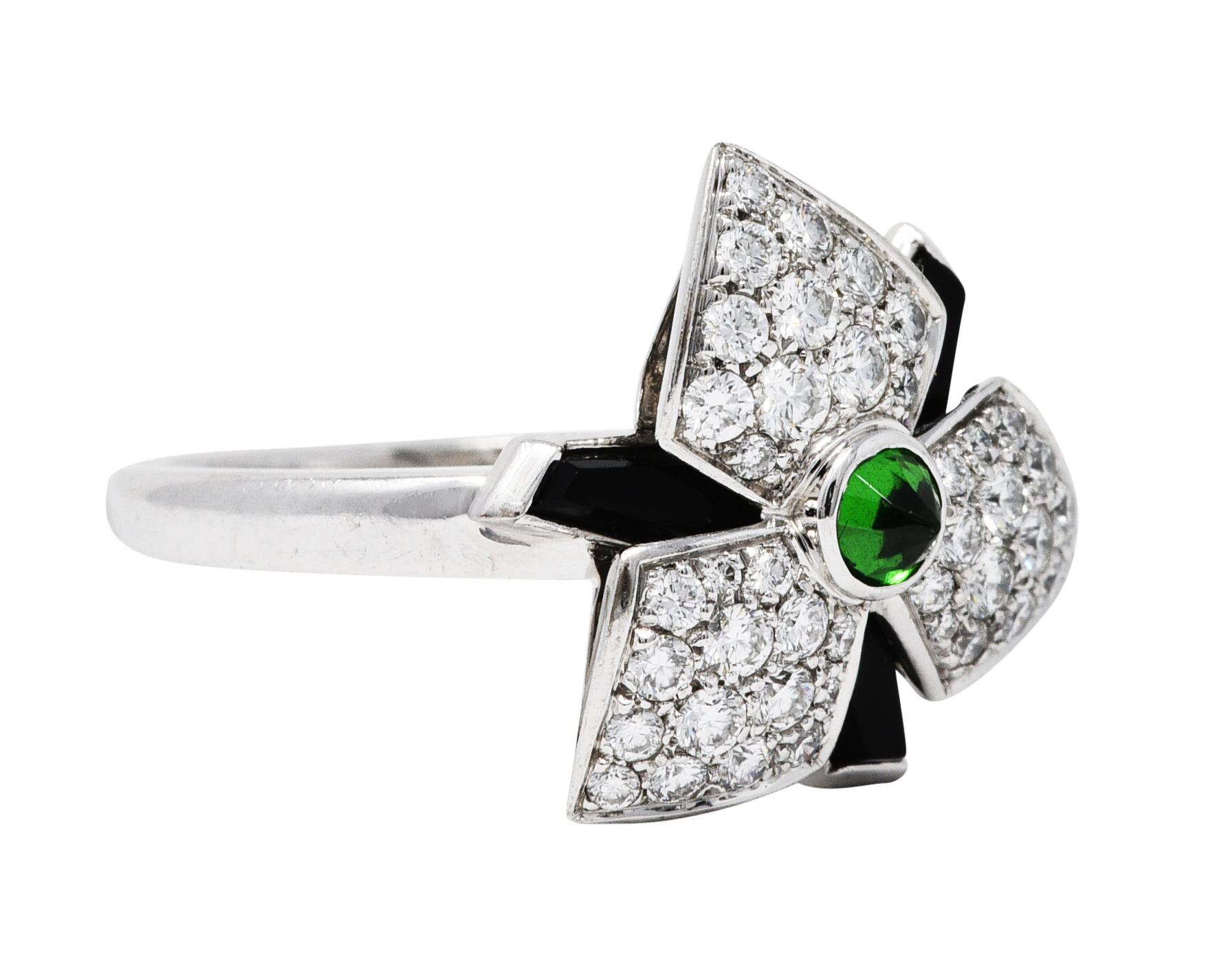 Designed as an orchid flower with highly stylized petals

Centering a reverse set 3.0 mm tsavorite garnet - viridian green in color

With calibrè cut onyx as geometric petals - opaque black with excellent polish and a minor chip

Featuring a triad