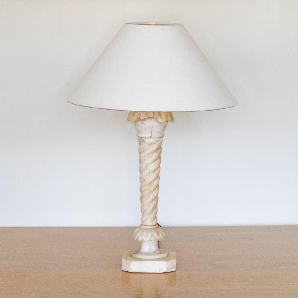 Incredible carved alabaster table lamp from France, 1950's. Unique twisted shape with carved base and beautiful carved leaf detail. One leaf chipped, see photos. Newly re-wired with a new linen shade.