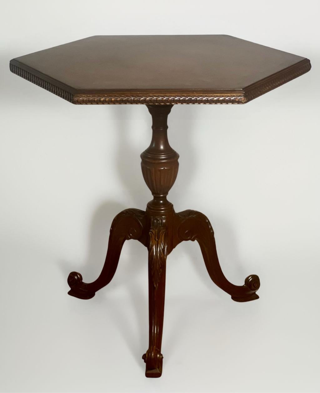 Exceptional French walnut burl hexagon shaped occasional, center hall or side pedestal table on a tripod base, circa 1930s. Richly carved with a book-matched and banded top with intricate stylized floral edge detail supported by an urn decorated