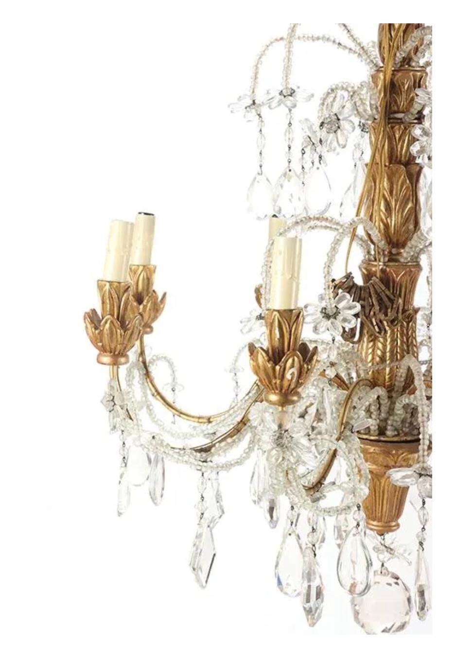 19th century Italian carved and giltwood chandelier. Chandelier has eight giltwood arms with gilt cups for lights, each connected to lovely hanging and floral beading. Additional beading on central gilt arm adds to all over beauty. 