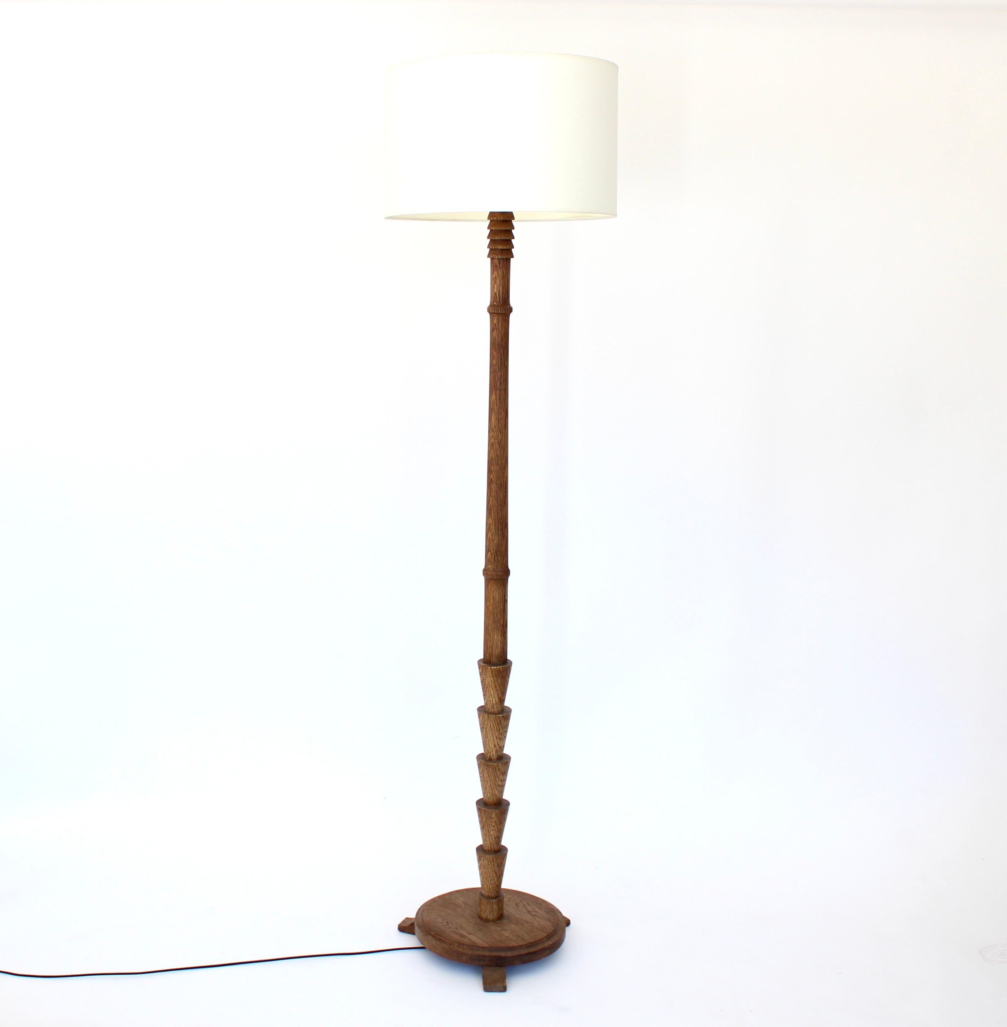 French carved and turned raw oak floor lamp with ivory linen shade. Wire brushed surface. The grain is raised and opened by that technique. 
Oak was always a favorite wood in c1940's for warmth of the color and this lamp has a beautiful patina.
The