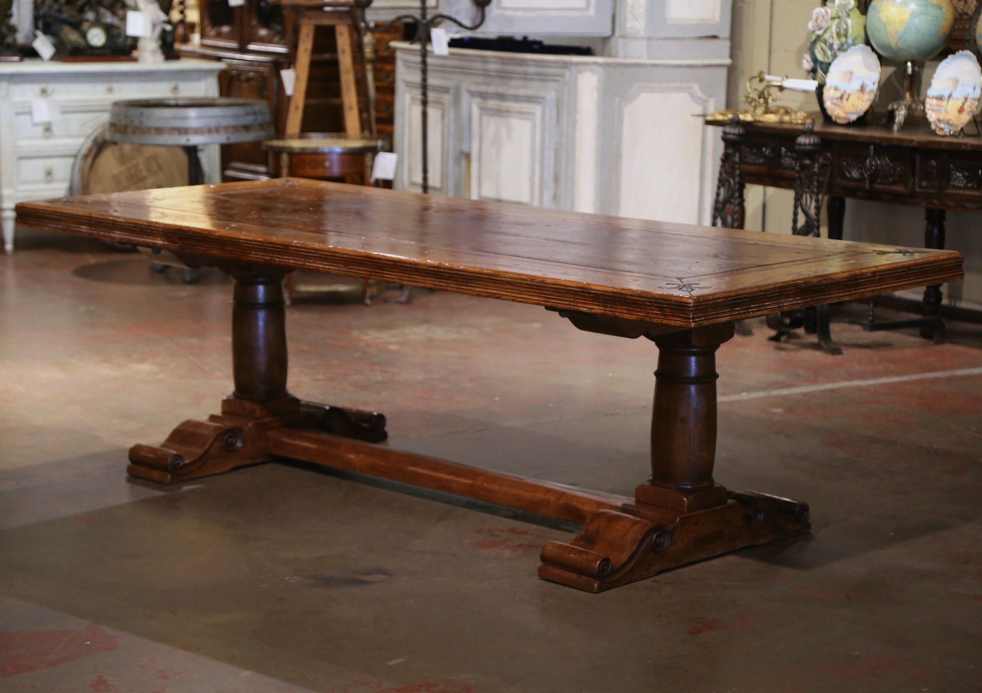 This elegant dining table was crafted in the Pyrenees of France using antique timbers, and following an 18th century design. Over 8 feet long, the large table sits on a trestle base, supported by hand carved turned baluster form support legs ending