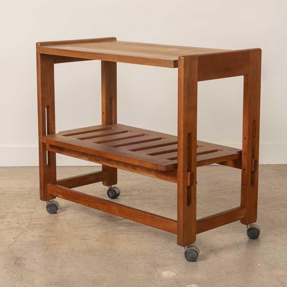Wonderful two tier oak wood bar cart in the style of Guillerme et Chambron from France, 1950's. Rectangular top and adjustable lower shelf with carved legs on four wheels. One peg missing from lower level, see photos. Original wood finish shows