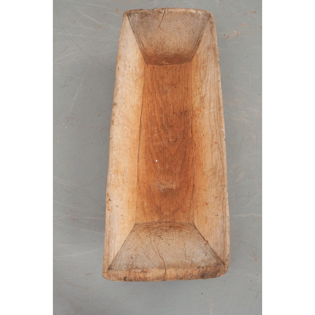 This is a French dough bowl, a wooden vessel used to mix bread dough. These bowls were found in every home and were typically carved from a large piece of wood. Now, it would make a nice conversation piece or decorate a dining room table. Circa