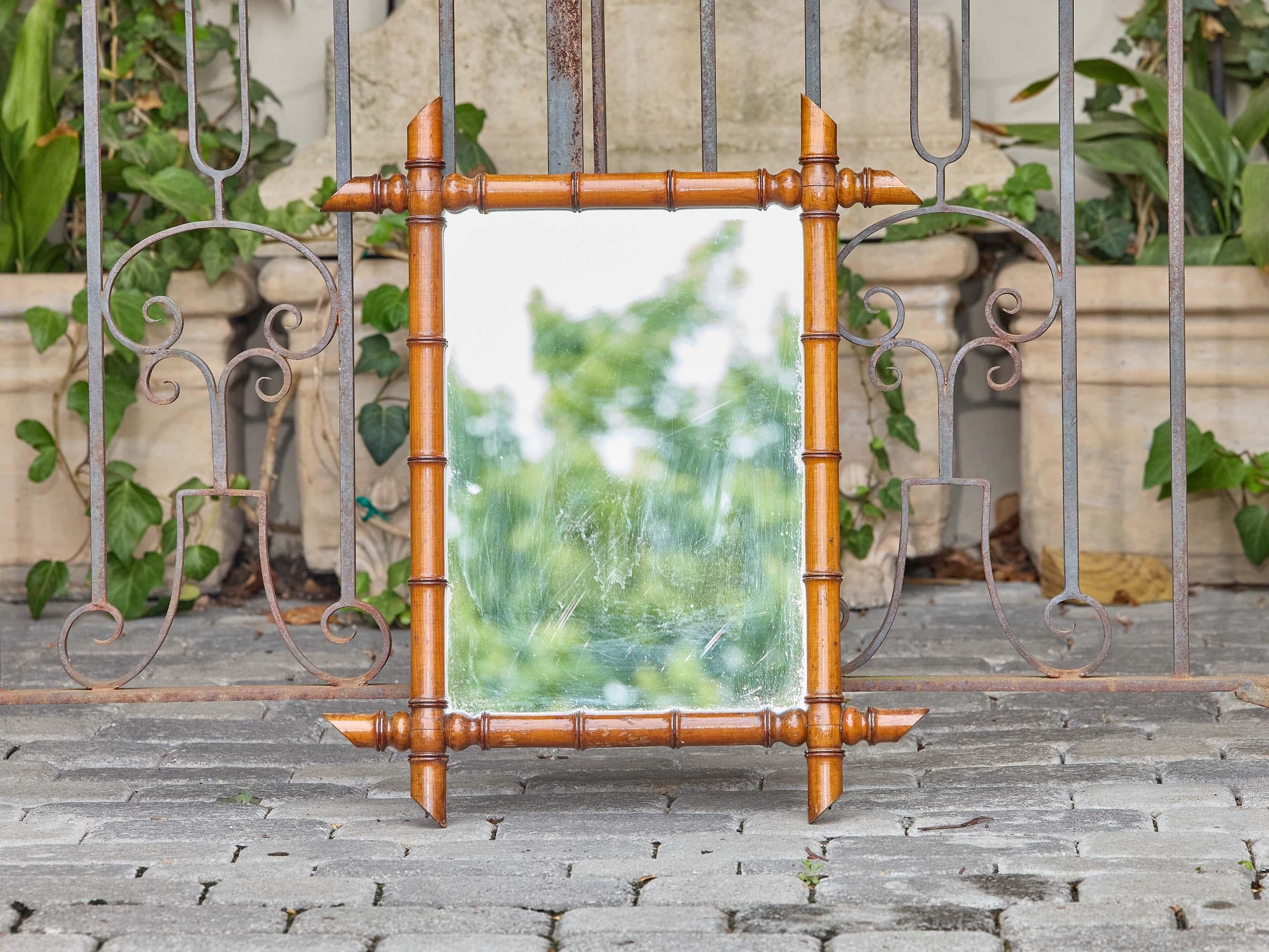 Ce miroir français en faux bambou, datant d'environ 1900, présente toutes les caractéristiques des sculptures inspirées du bambou du début du siècle : tiges articulées, nœuds arrondis et épis de faîtage très effilés ancrés dans chaque coin. Le cadre