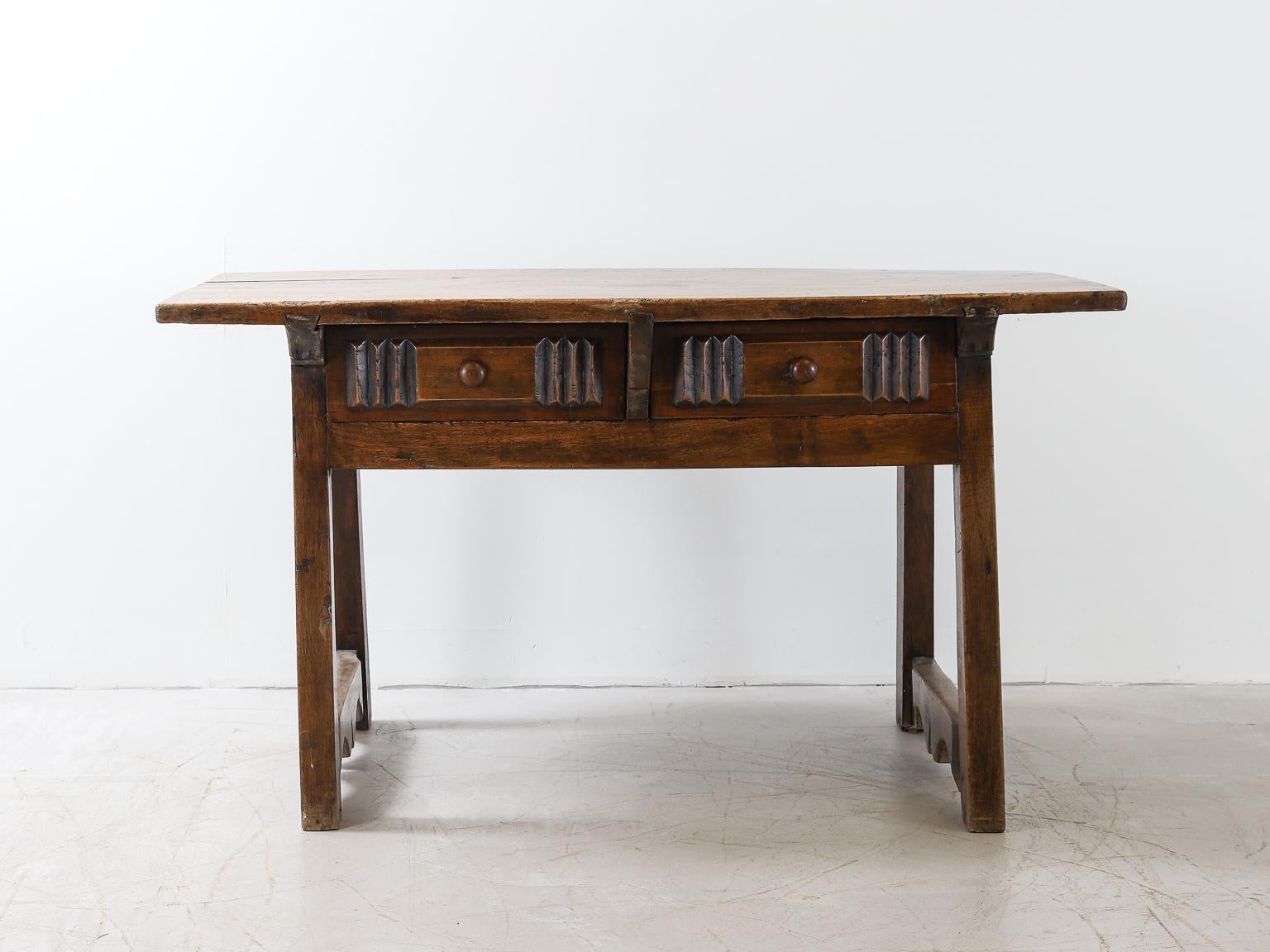 A French carved side table or desk in rich coloured fruitwood; with two drawer frieze, angled legs joined by decorative stretchers, carved wood back panel with decorative patterns etched into the wood, and a wonderfully patinated top.