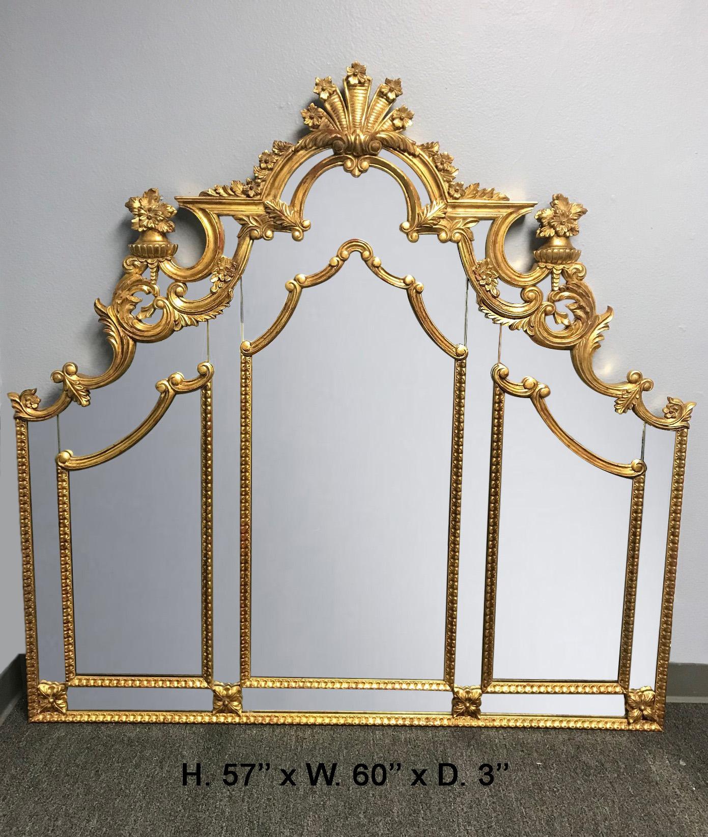 An impressive French carved giltwood and mirrored headboard, late 20th century. 

The headboard is surmounted by a shaped Rocaille motif giltwood crest decorated in shells and foliage, above a conforming mirror plate with three gilt mirrored