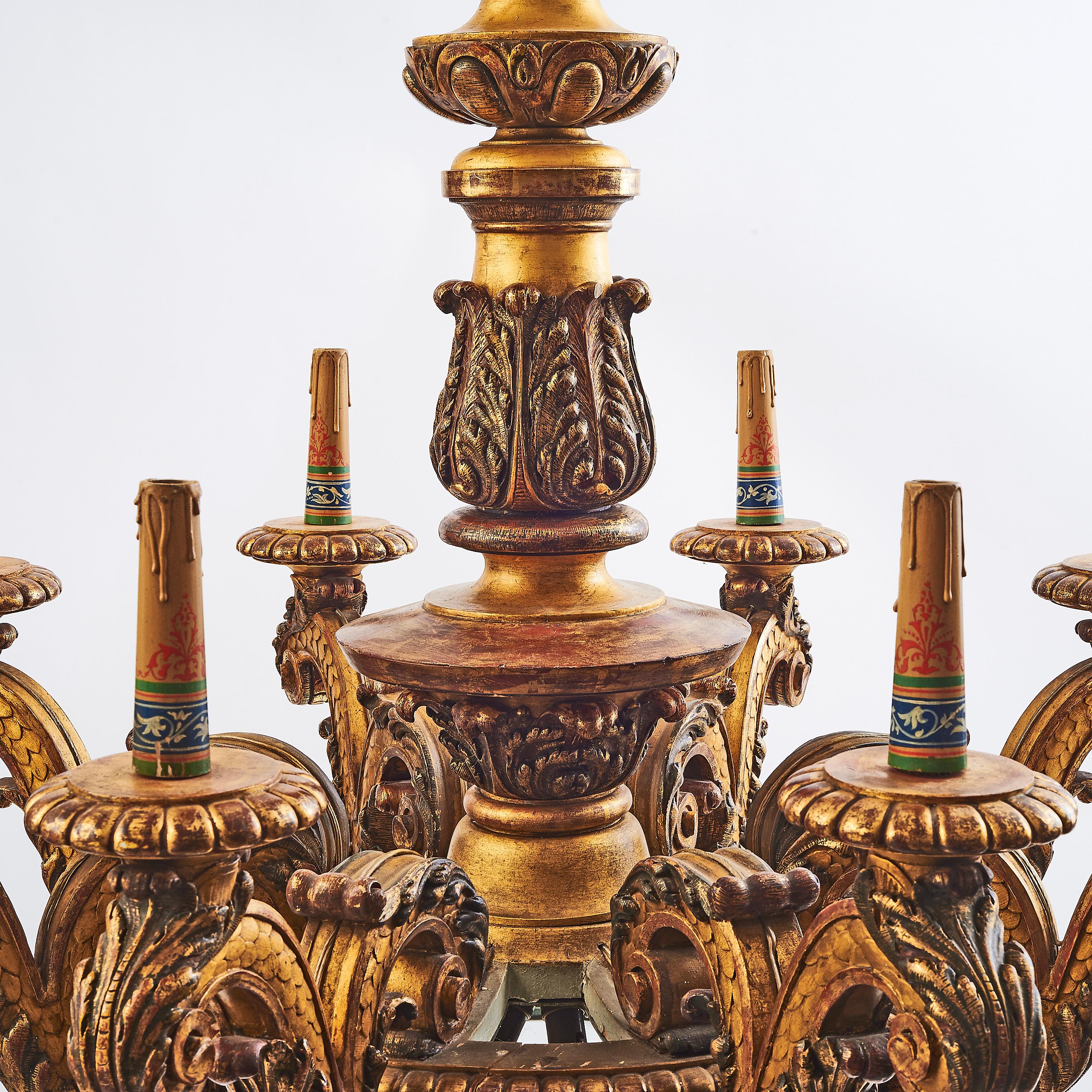Large highly carved giltwood Baroque style chandelier, circa 1900. The central column punctuated throughout with rich foliate carving, below this eight outwardly scrolling arms, with a scale design and acanthus leaf underside, the arms each finished