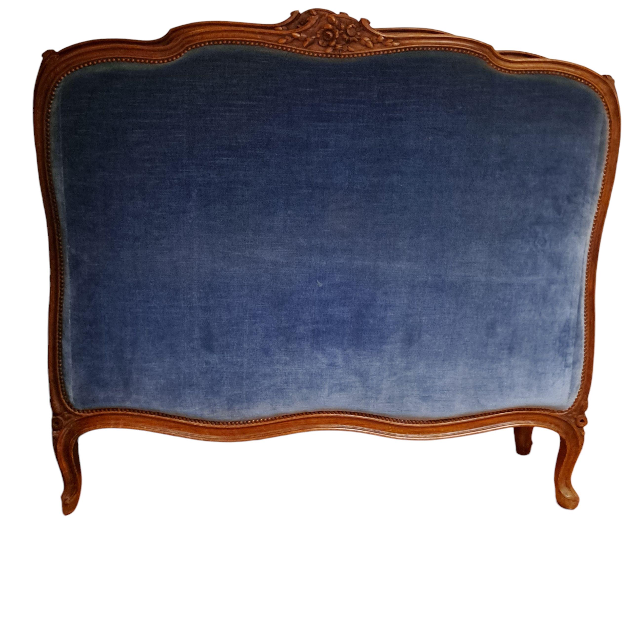 French Louis XV carved walnut bedframe with blue velvet upholstery.
