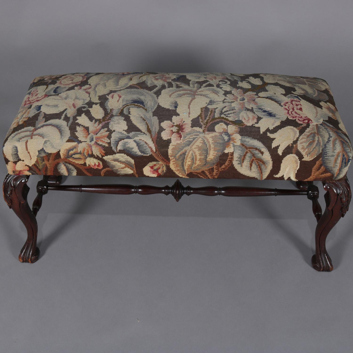 Antique French bench features carved mahogany frame with cabriole legs having acanthus knees and turned stretcher, upholstery is tapestry in foliate design, circa 1890.

Measures: 19