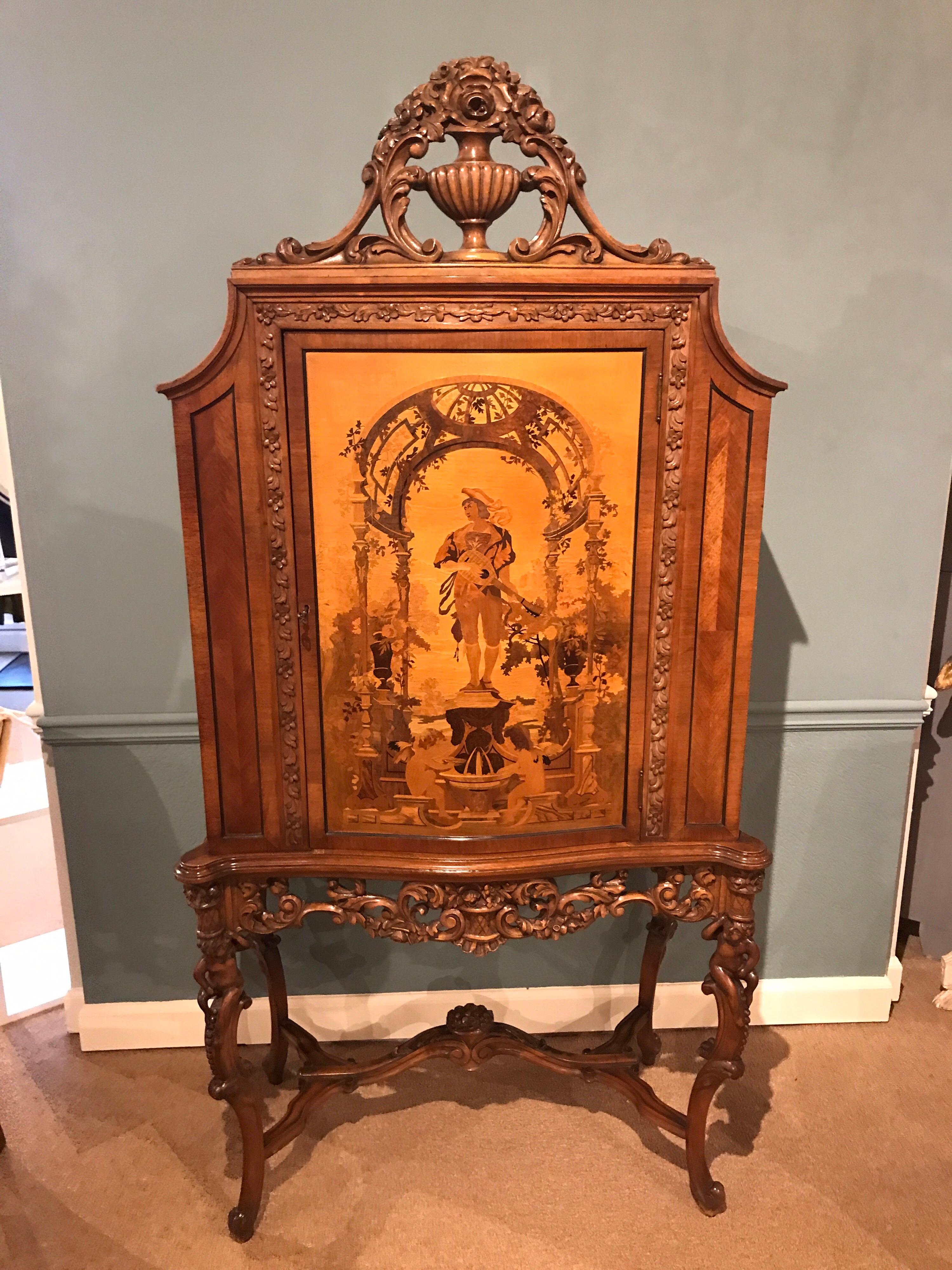 French carved marquetry cabinet, with single door, profusely inlaid with exotic woods of a garden scene. Fitted with four adjustable 28
