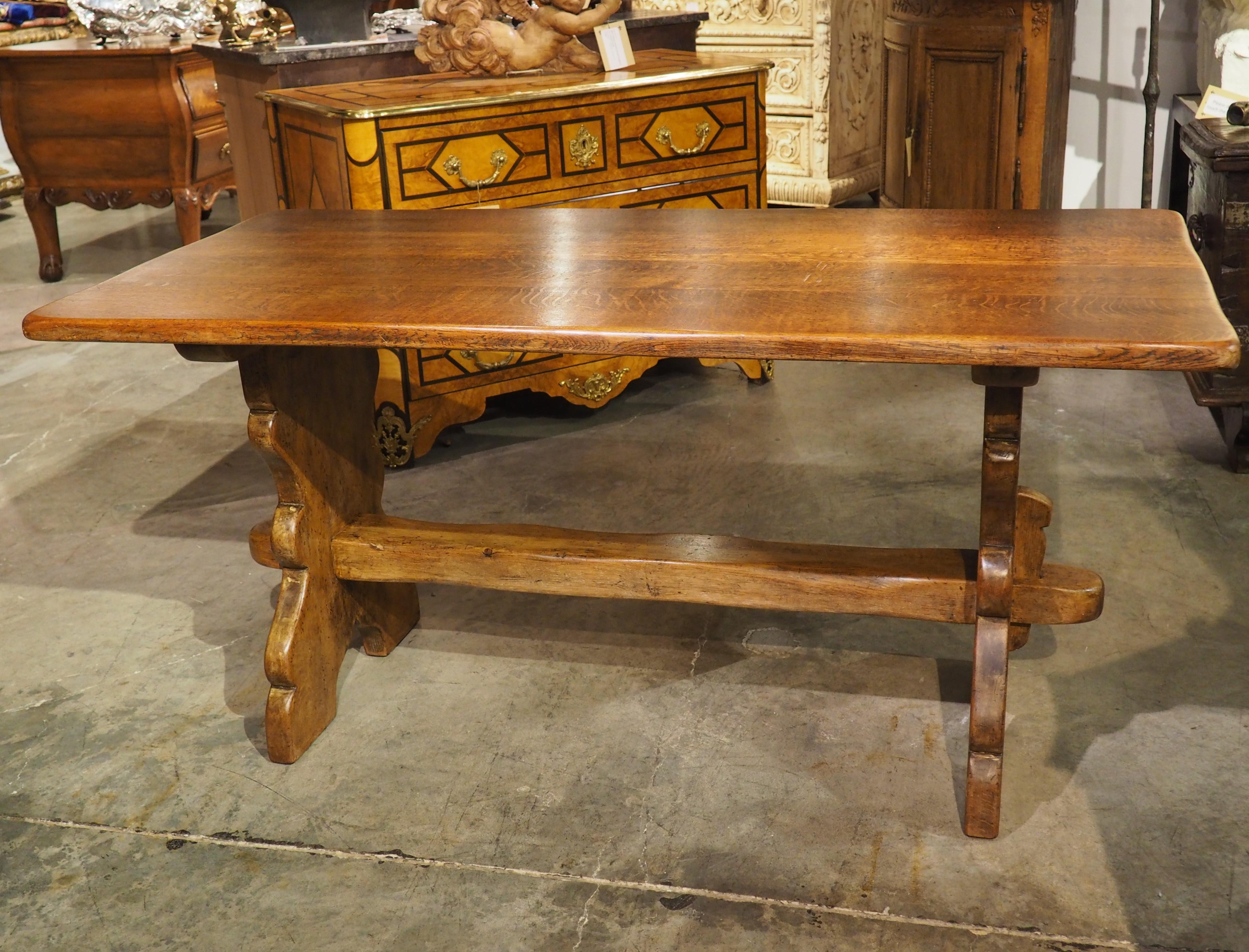 With ample character and rustic charm, this oak and pine table would be a fantastic addition to any household. Hand-carved circa 1950s in the Pyrenees Mountains of France, the top and the stretcher have subtle undulating edges that enhance the