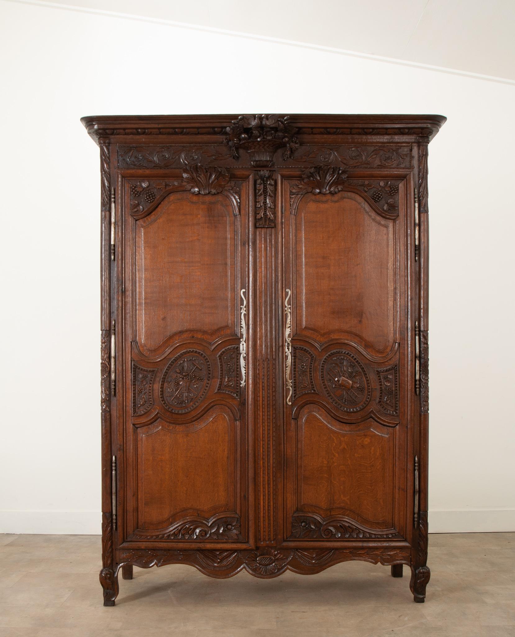 This stunning armoire de mariage was crafted in France during the 1800s from richly toned solid oak. The ornately carved motifs represent the wishes of wealth and prosperity for the new couple. The cornice has an impressively carved woven basket
