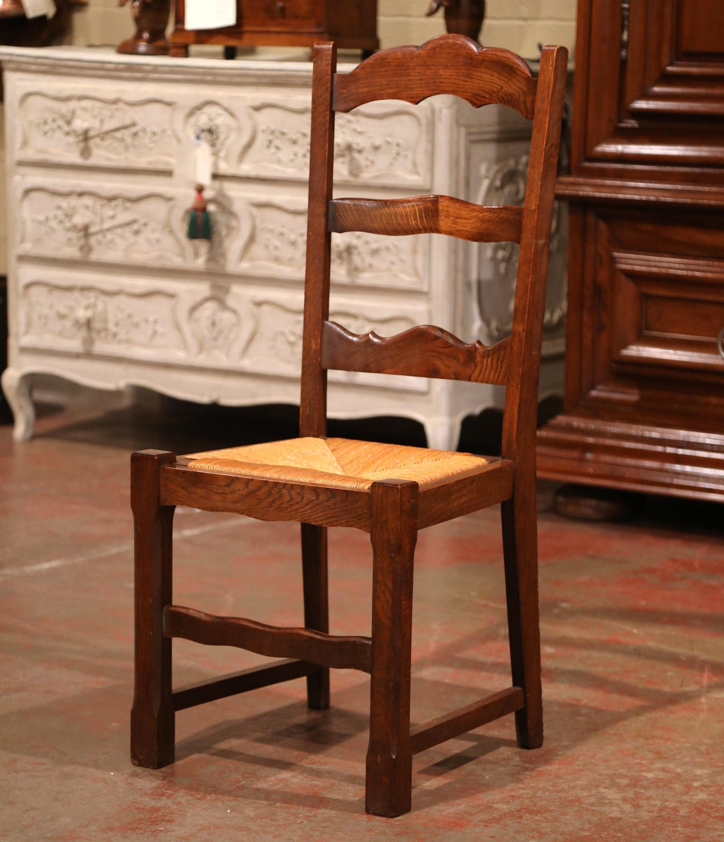 This elegant set of country chairs was crafted in France, circa 1980. Carved from solid oak, each chair has three carved ladders across the tall pitched back which give each chair great support and comfort. The seat has woven rush surface over four