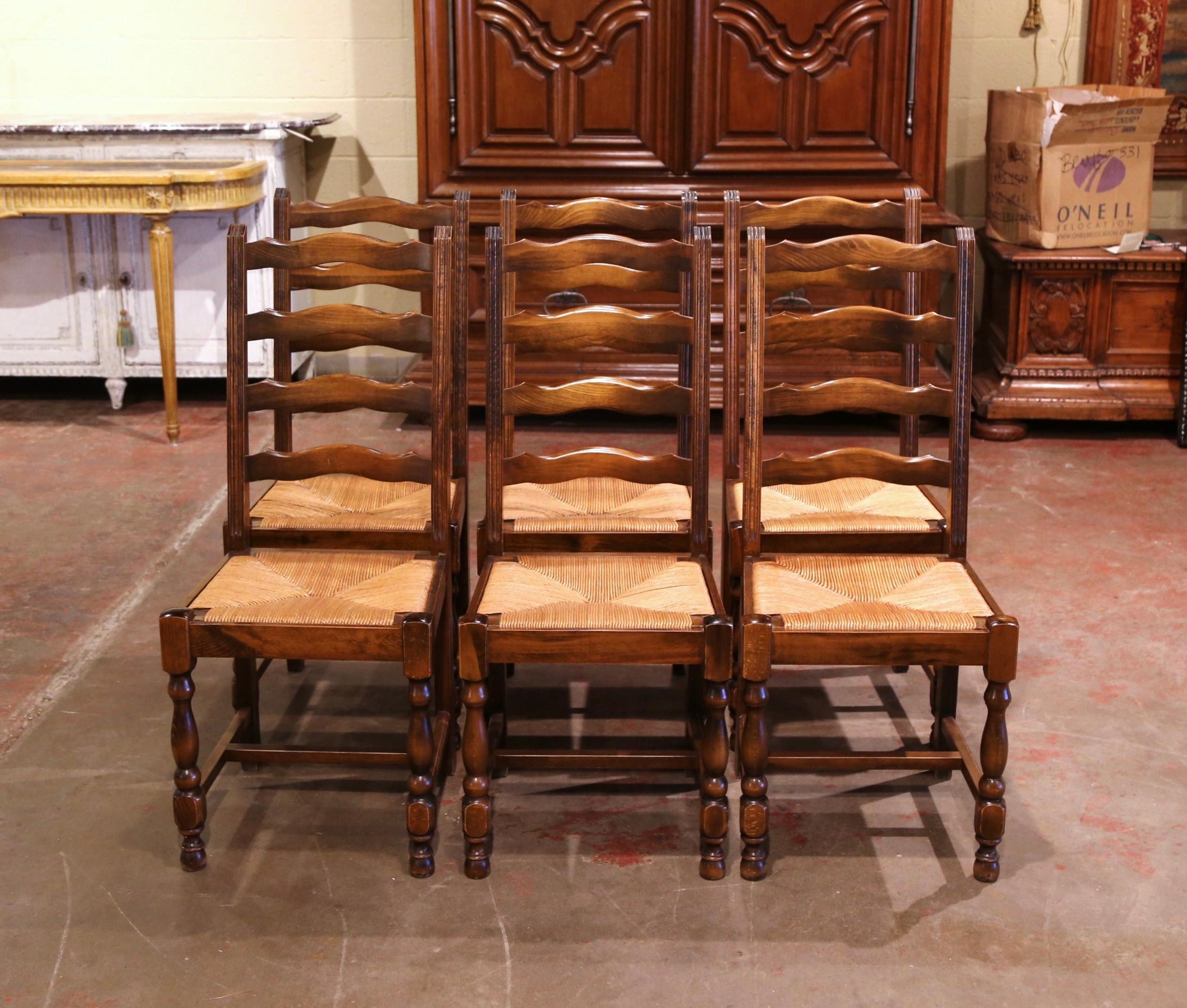 This elegant set of country chairs was crafted in France, circa 1980. Carved from solid oak, each chair stands on front turned legs, and has four carved and scalloped ladders across the tall pitched back which give each chair great support. The