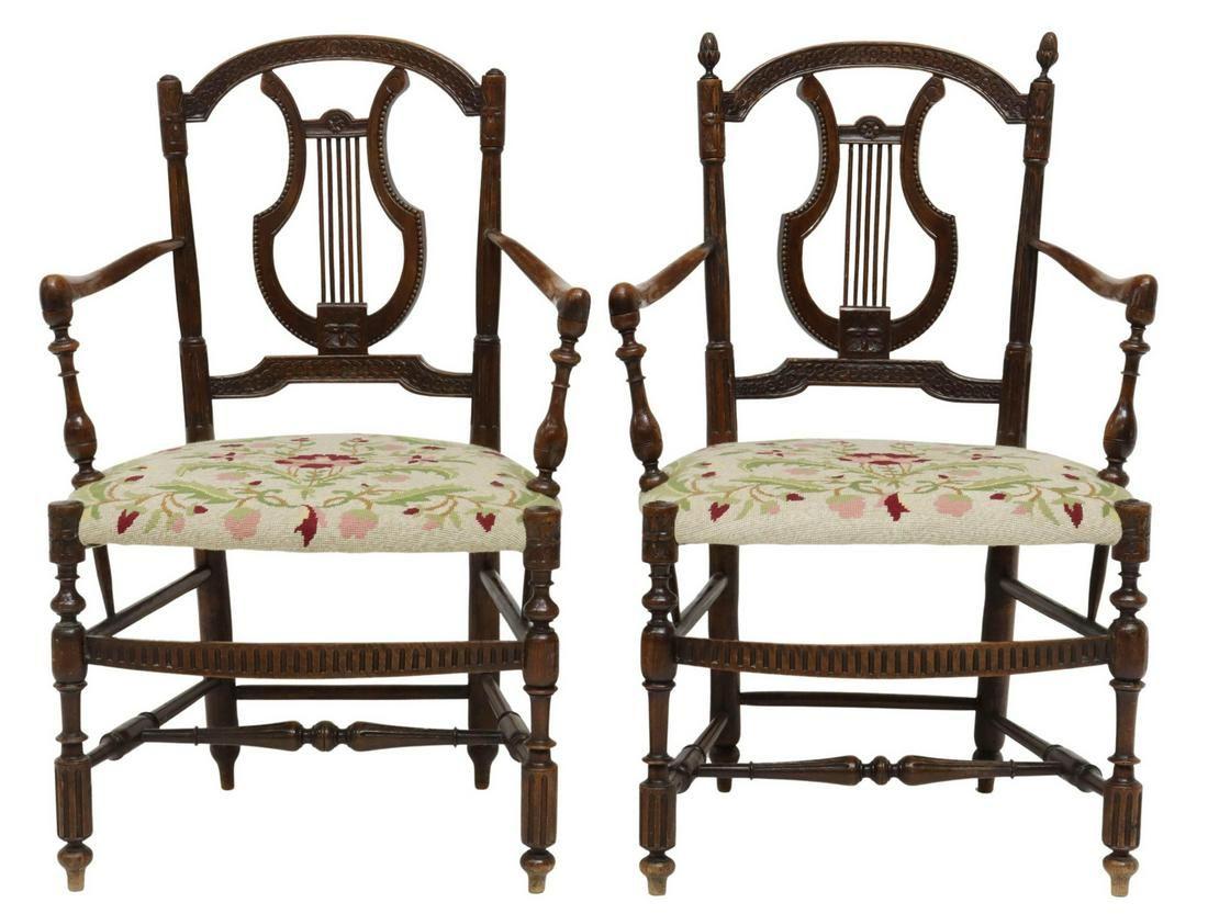 Antique French oak lyre-back armchairs, late 19th c. The armchairs have carved frame with interlocking ring ornamentation, gently curving arms, centering padded seat, upholstered in vining floral pattern needlepoint, rising on turned and fluted