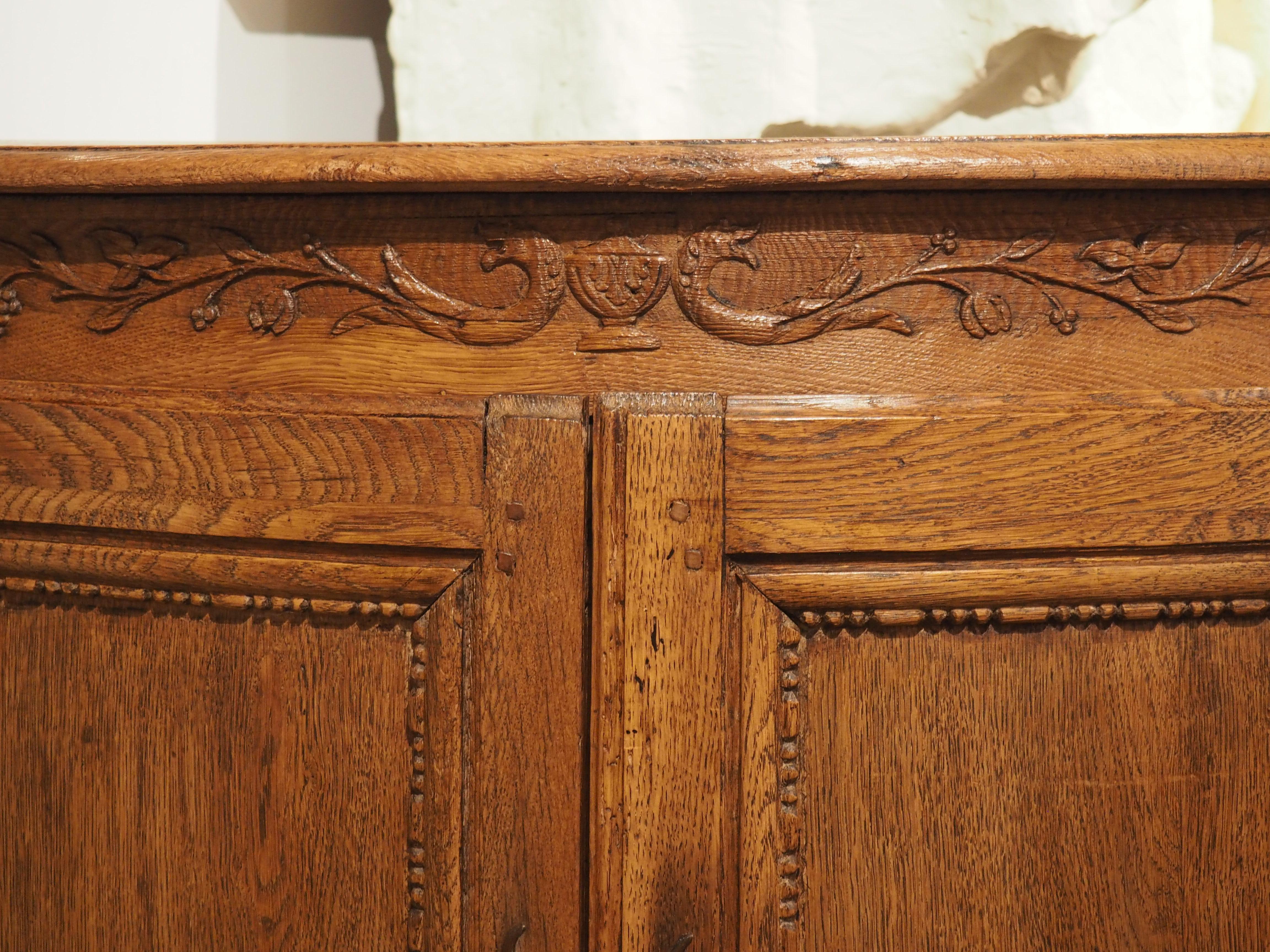Bringen Sie mit diesem exquisiten französischen Eckschrank aus dem 18. Jahrhundert einen eleganten Touch in Ihr Zuhause. Das sorgfältig aus Eichen- und Obstholz gefertigte Möbelstück verfügt über ein keilförmiges Innenfach, das mit zarten