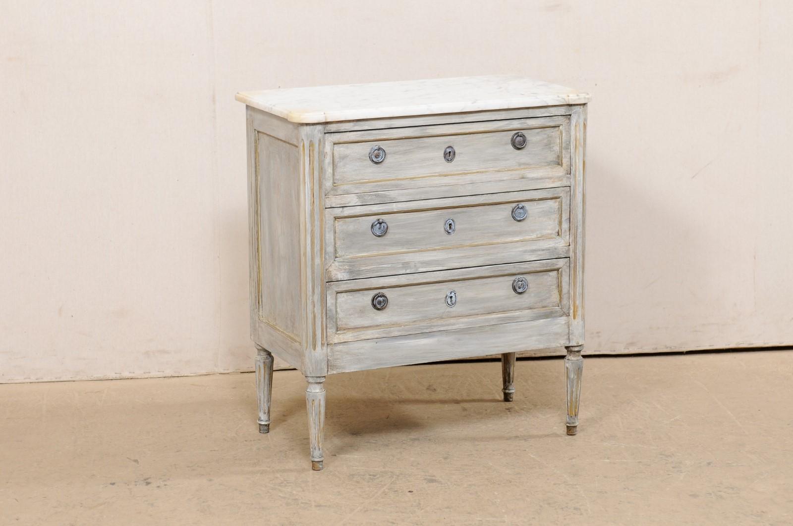 Cassapanca francese in legno dipinto e intagliato con piano in marmo, risalente agli inizi del XX secolo. Questo antico cassettone francese presenta un piano in marmo bianco di forma rettangolare con venature grigie e angoli frontali pronunciati e