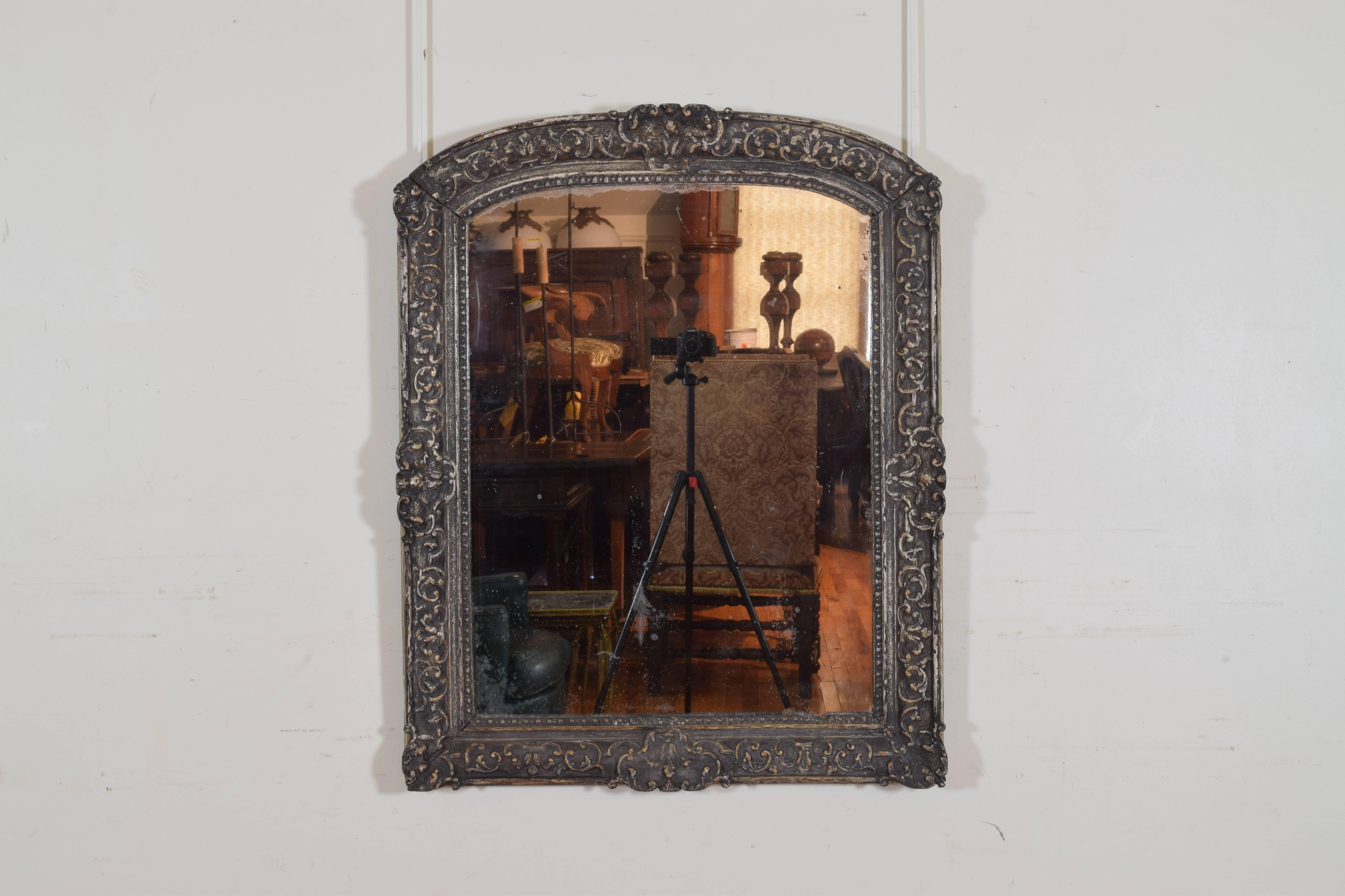 This carved wood mirror would originally been gilded but is now only showing traces of gilding in the high areas.