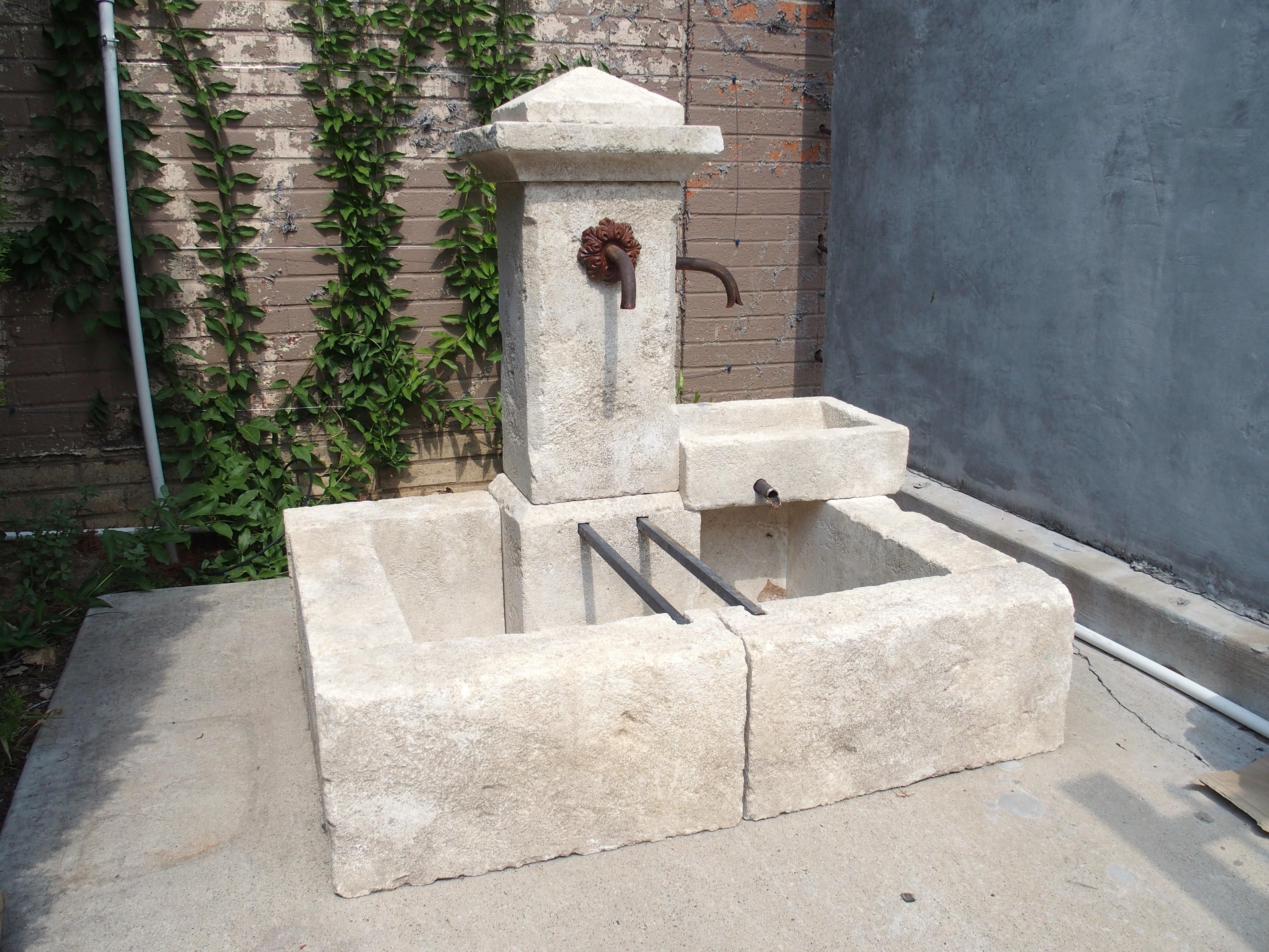 A very charming limestone fountain from France, this single-pillar fountain has a side-mounted basin that acts as a spill bowl into the larger rectangular basin. Consisting of 11 pieces of individually carved limestone sections, the pillar rises