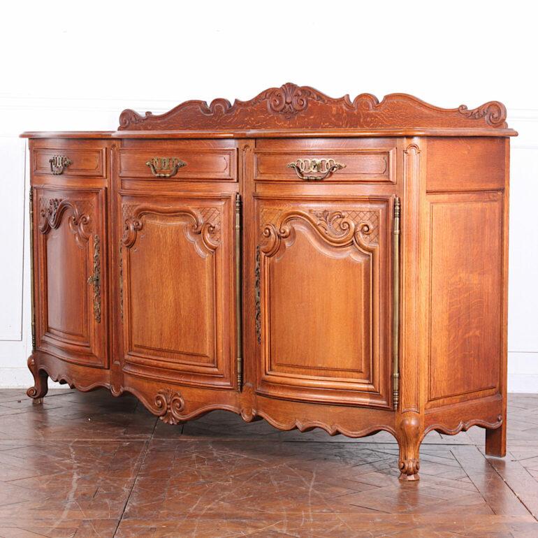 A top quality Belgian or French Louis XV style buffet constructed of solid white oak throughout. Three curved doors with elaborately carved frames and curved solid oak fielded panels; three drawers above with carved shaped fronts and hand-cut
