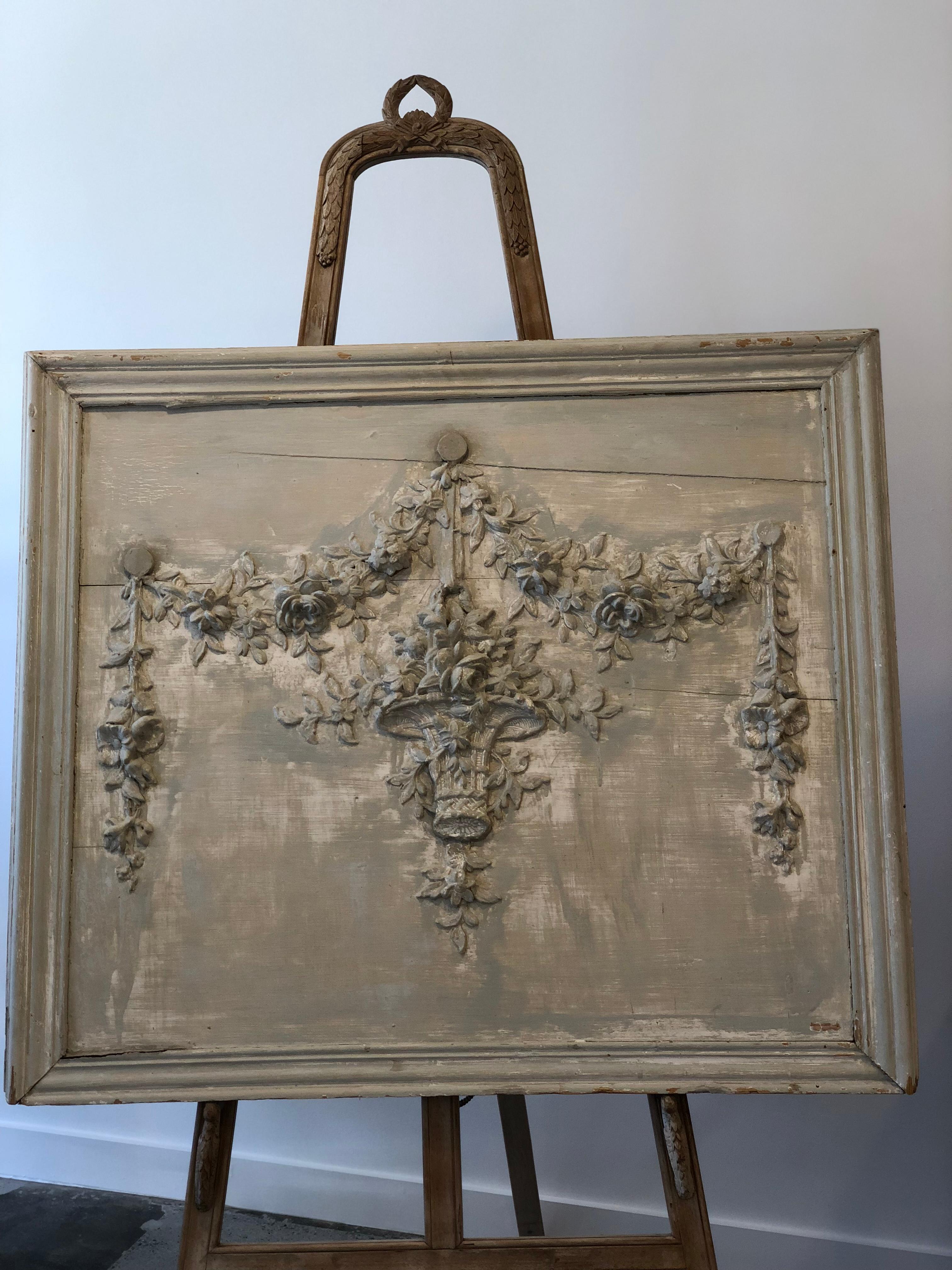 This lovely French carved board depicts a lovely basket with overflowing garlands. It is set on wood backboard. It is very textural piece that would be a nice backdrop in a variety of rooms. The color is a very soft faded mint green with hints of