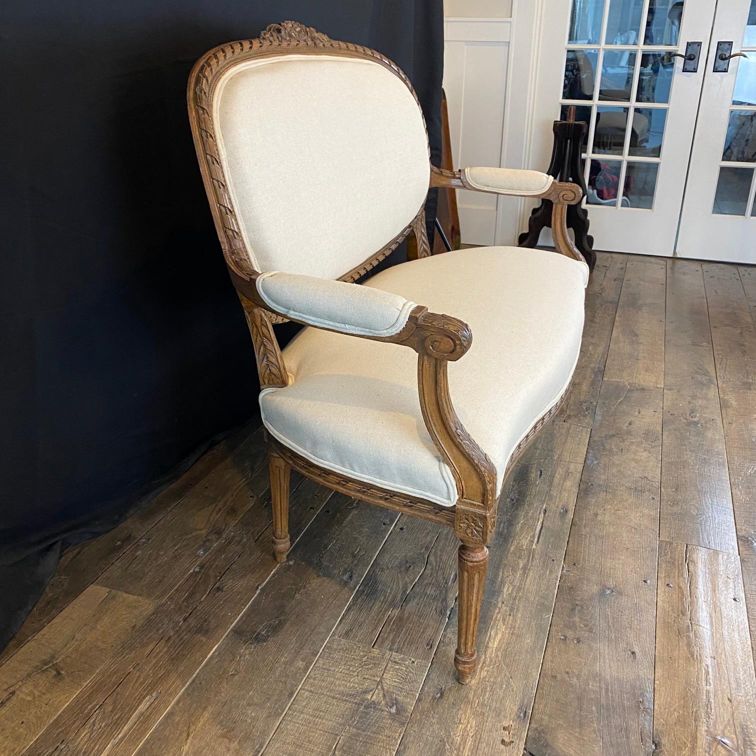 Sofá, loveseat o settee de nogal antiguo tallado, elegante y bien hecho.  Ejemplo clásico del estilo francés Luis XVI: la calidad es soberbia, el armazón tiene una talla nítida e intrincada por todas partes, y la nueva tapicería complementa los