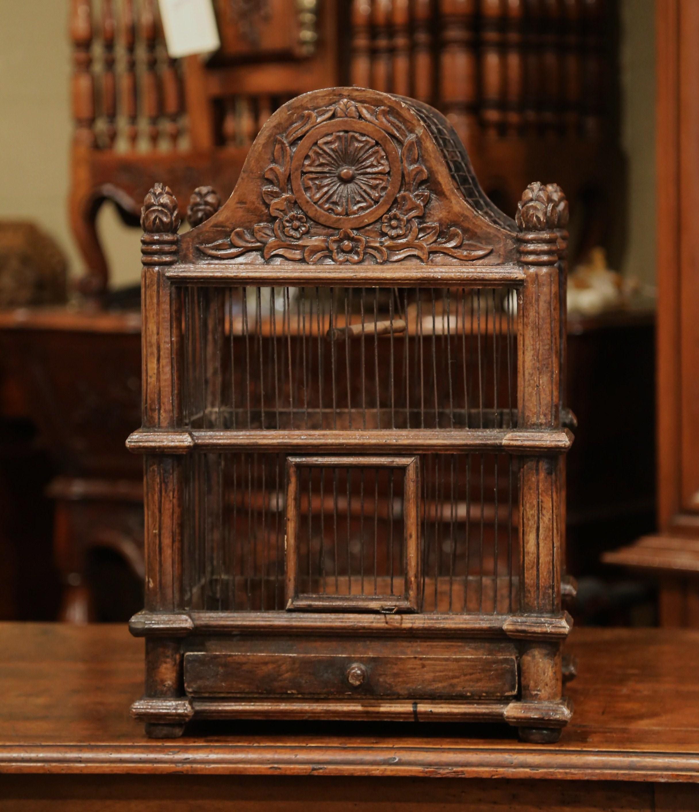 Bring the outdoors in with this large, elegant birdcage. Crafted in France, circa 2010, the carved walnut cage is decorated with a central carved medallion, and an arched dome top embellished with decorative finials in the corners. The cage is