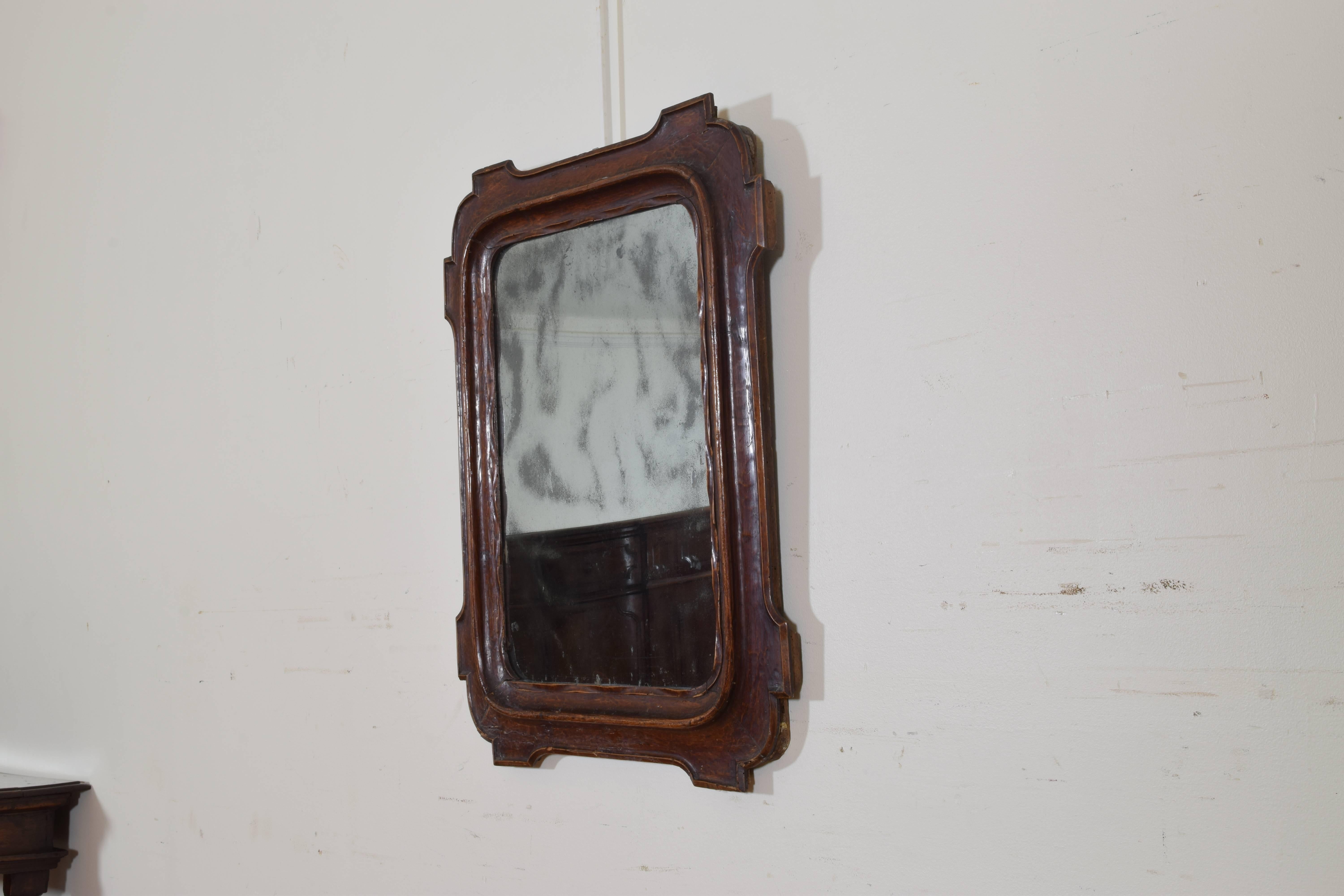 Having rounded an notched corners and a carved inner molding, retaining antique mirrorplate.