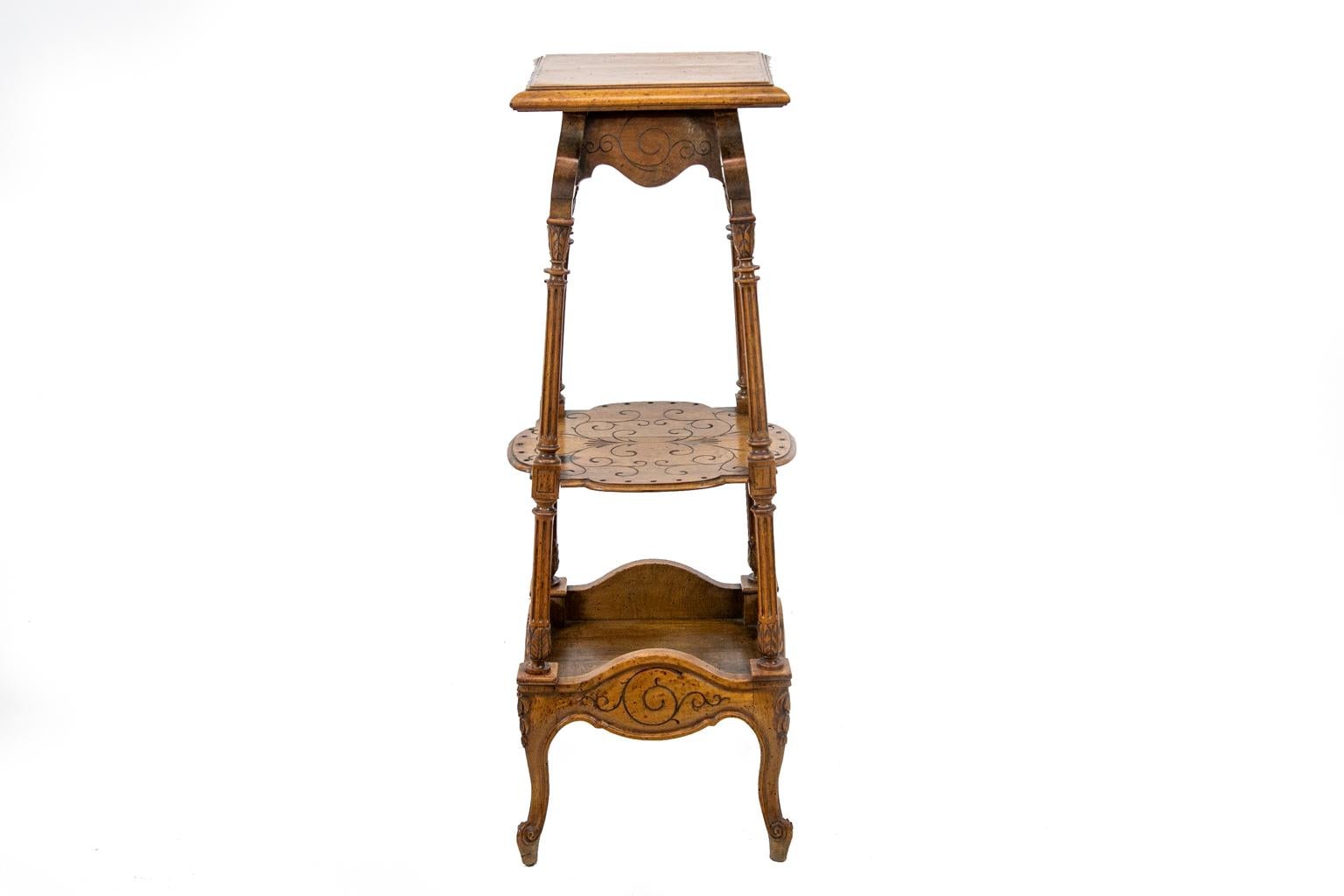 French carved walnut three tiered stand, with the aprons and middle shelf having incised carved arabesques. The support columns are fluted with acanthus leaf capitals and bases. The base terminates in carved french scrolled feet.