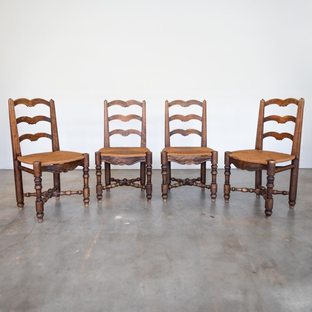 Beautiful set of four carved wood chairs from France, 1940s. Intricate carved wood legs and wood frame with floral detail. Newly replaced woven rush seats. Original wood finish shows great age and patina. Sold as a set of 4. 